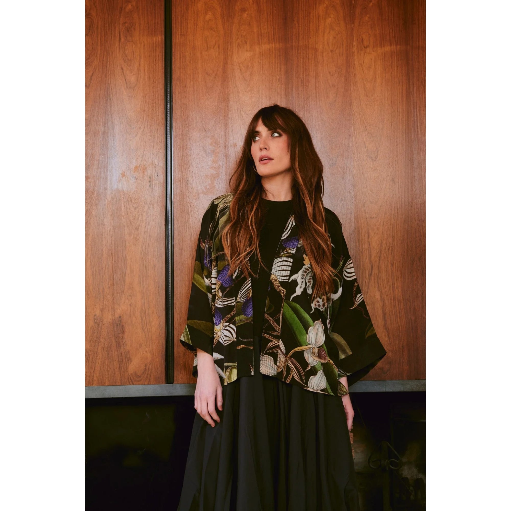 Woman wearing a patterned jacket against a wooden wall