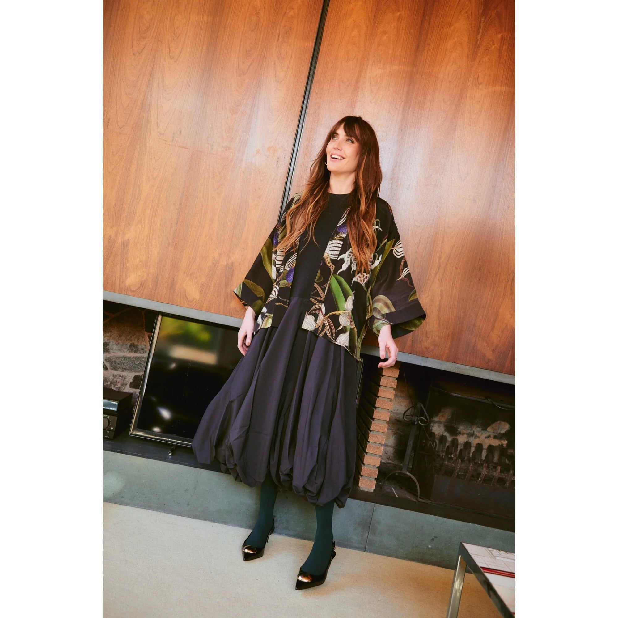 Woman in a stylish outfit standing in front of a wooden wall.