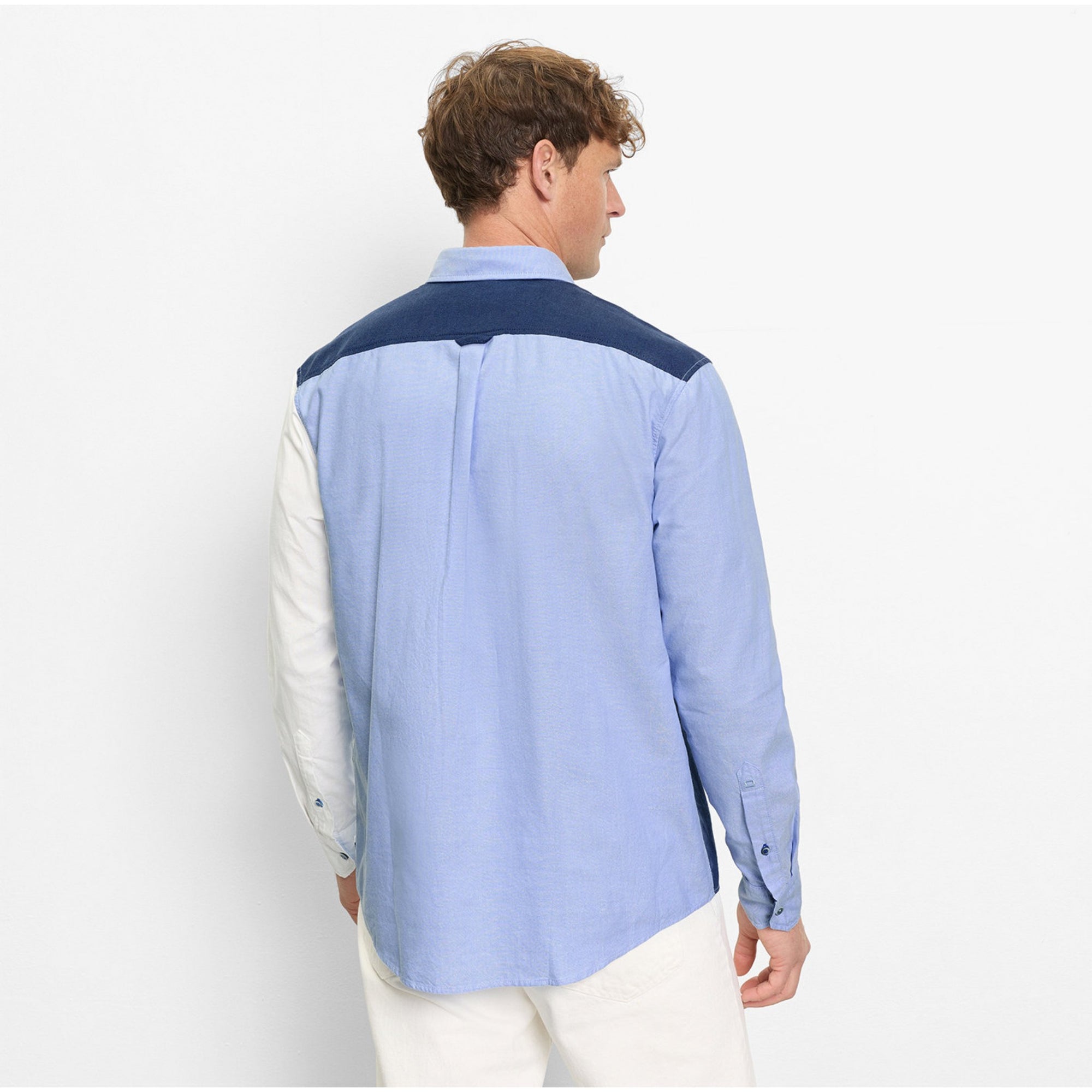 Person wearing a blue and white shirt with a plain background