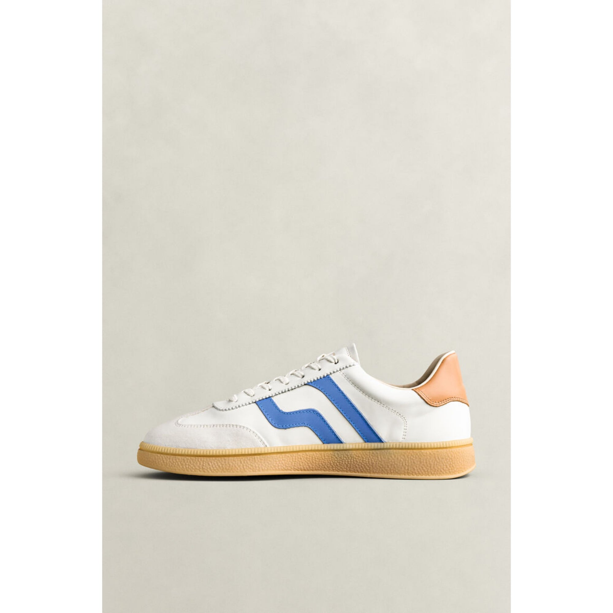 White sneaker with blue stripe on a light gray background