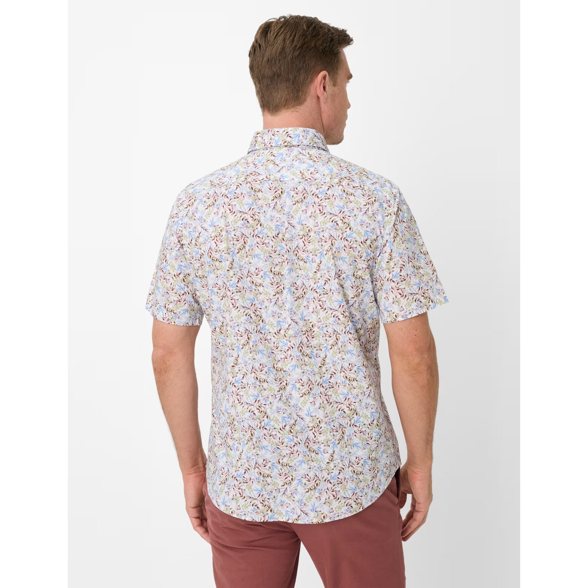 Man wearing a short-sleeve floral shirt and pink pants on a white background