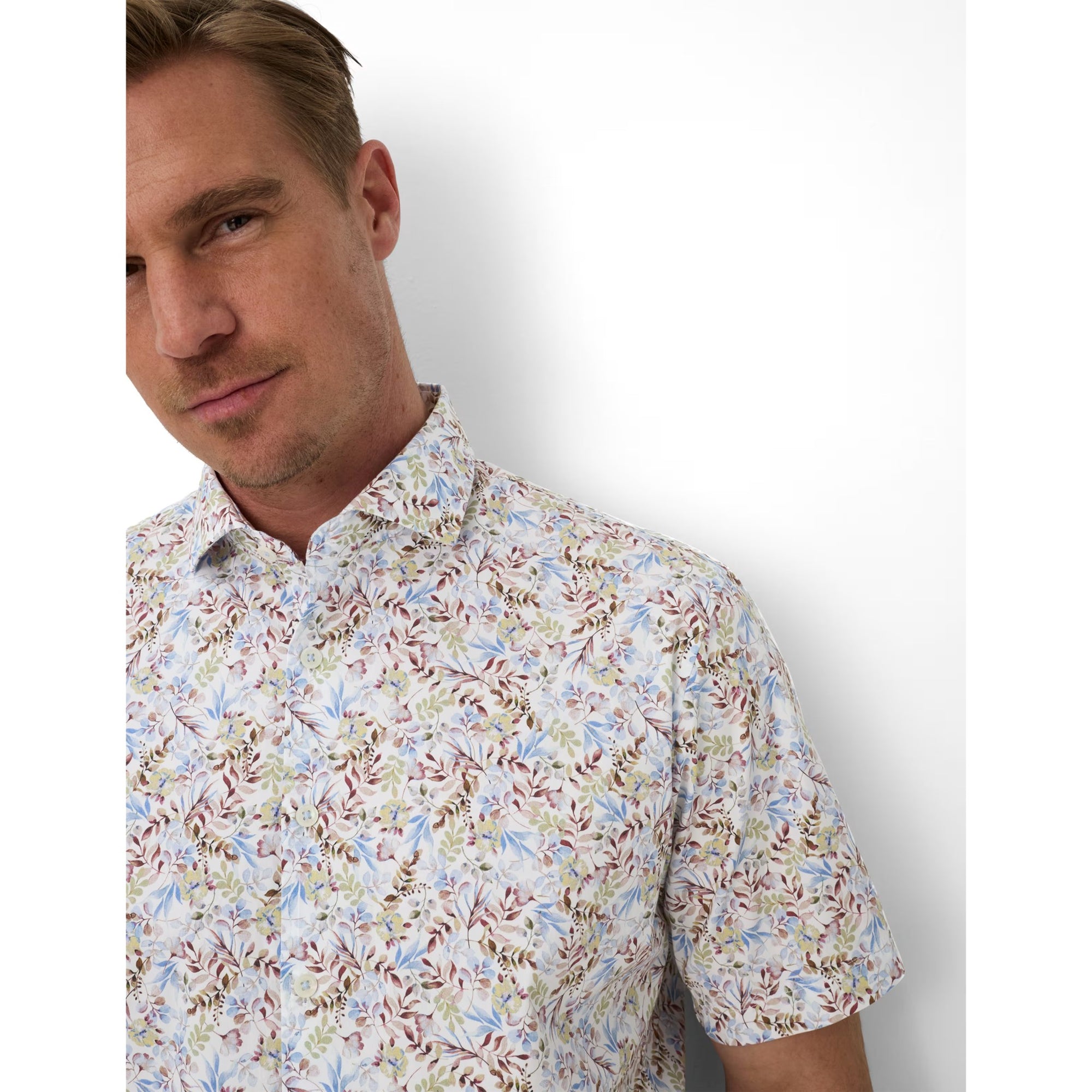 Man wearing a floral short-sleeve shirt against a plain background