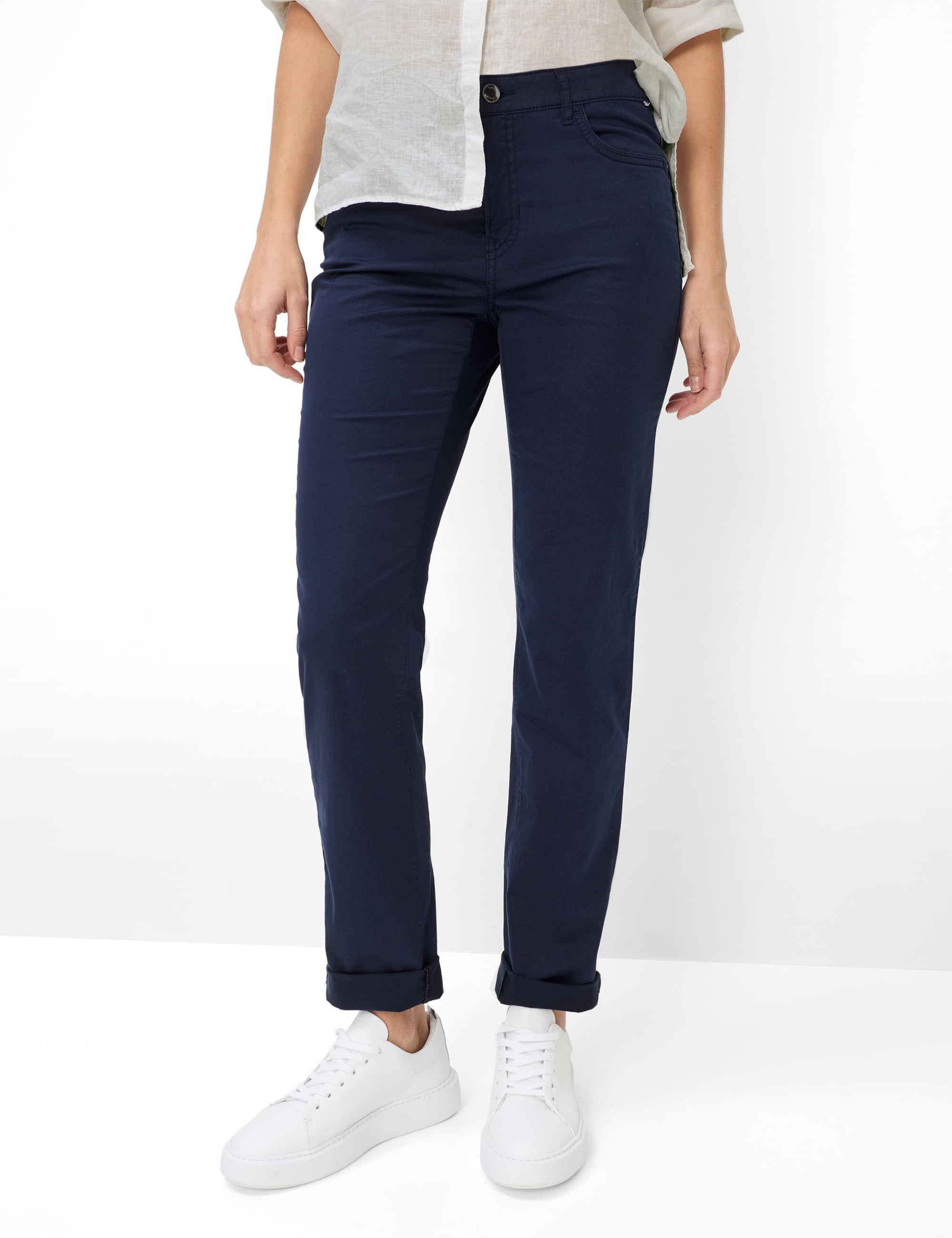 Person wearing navy pants and white sneakers on a white background