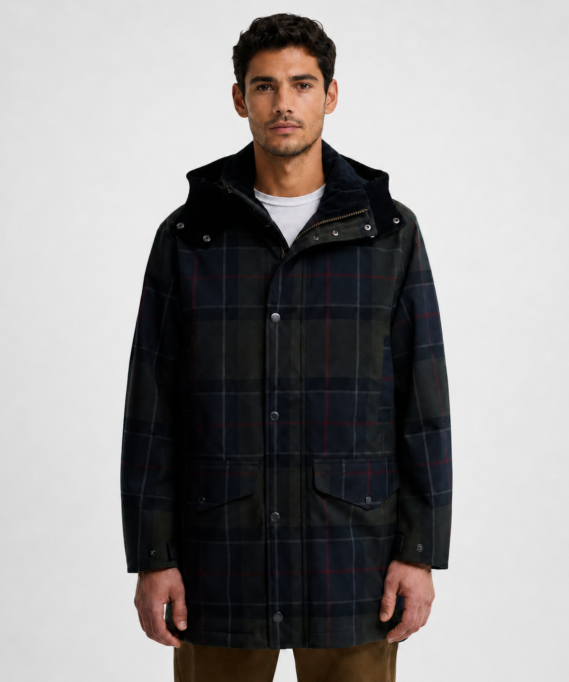 A man wearing a Waterproof Barbour dark navy and black plaid hooded jacket with red and white windowpane lines, photographed against a plain light gray studio background.