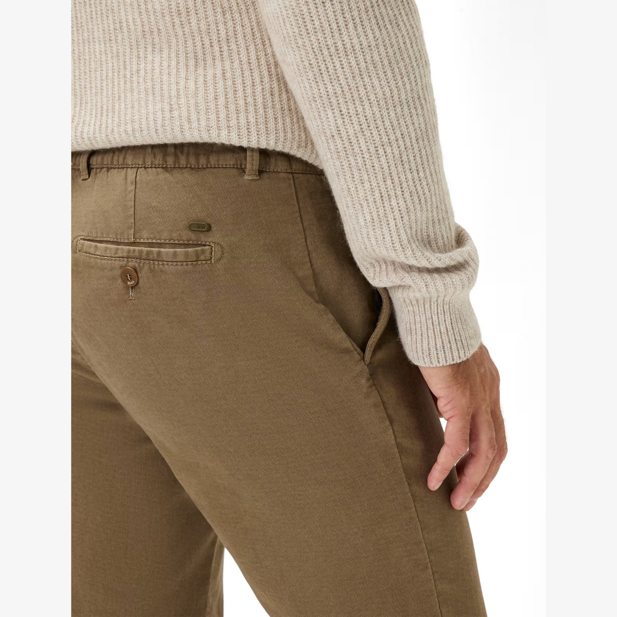 Brown pants worn with a beige sweater on a white background