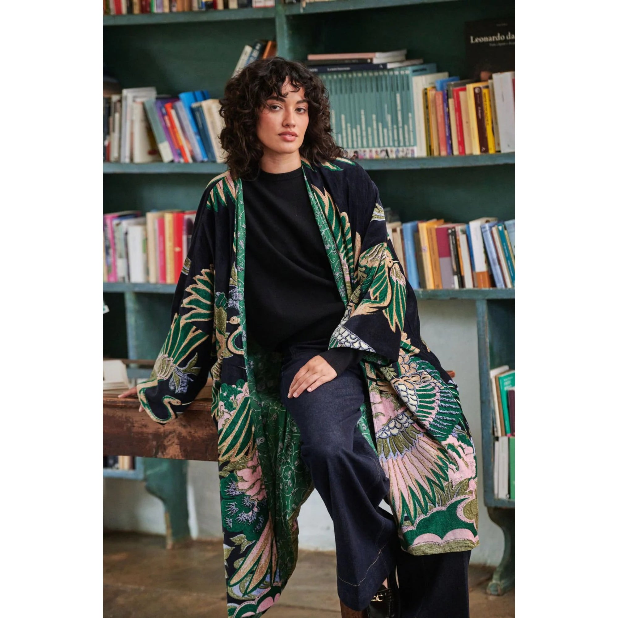 Woman wearing a floral kimono in front of a bookshelf