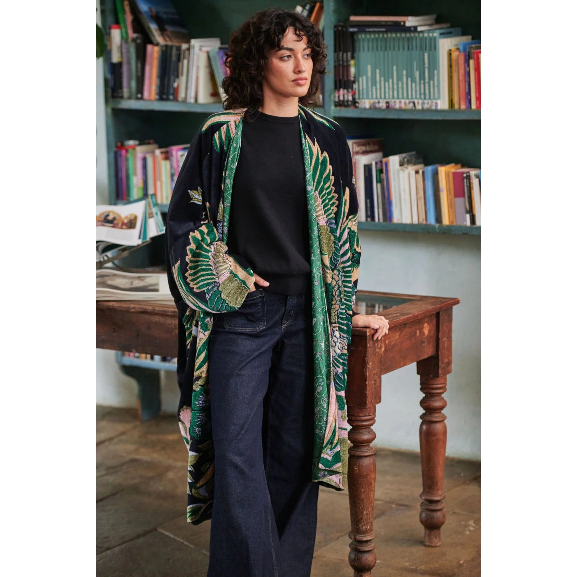 Person wearing a patterned kimono in a room with bookshelves.