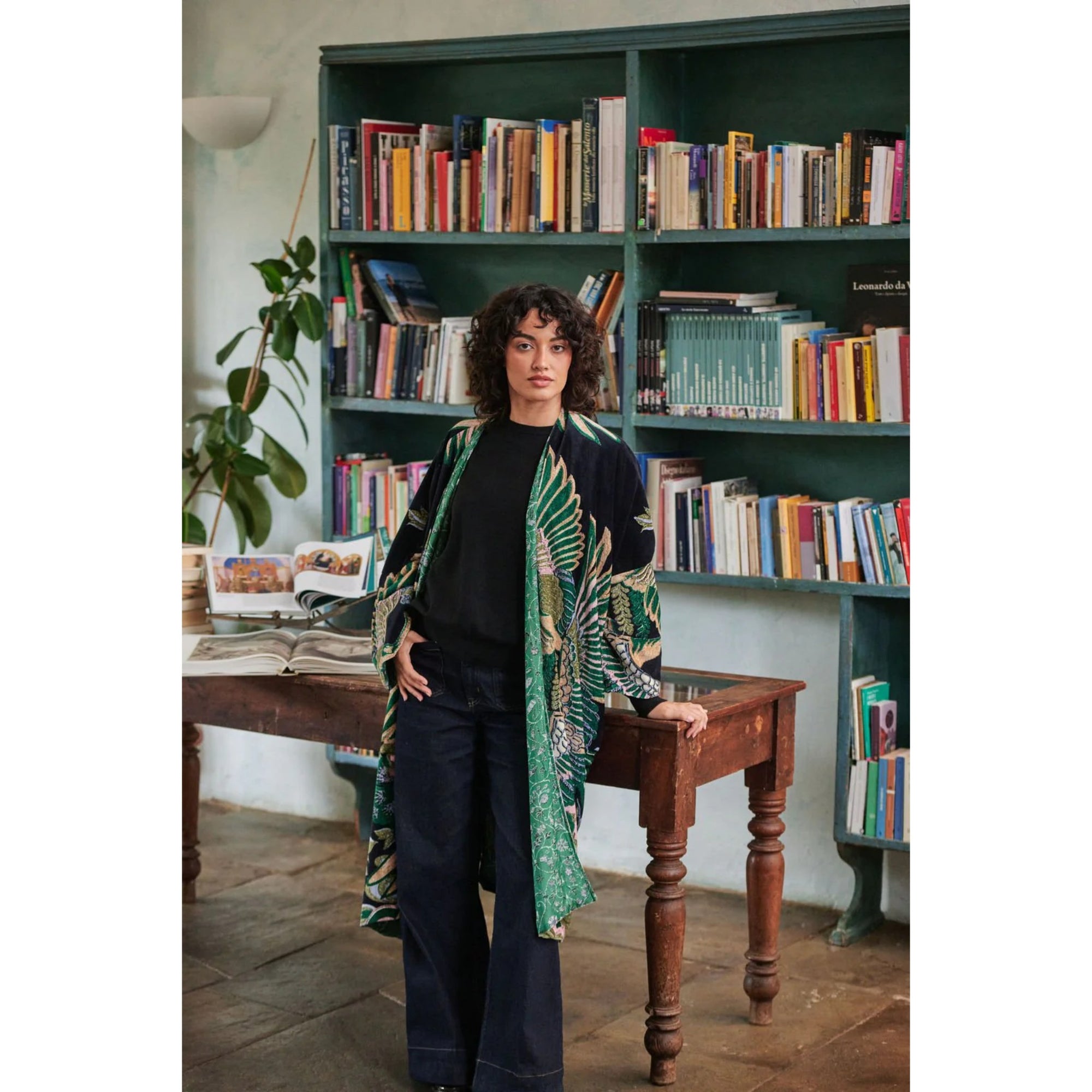 Woman standing in a room with bookshelves and a wooden table.