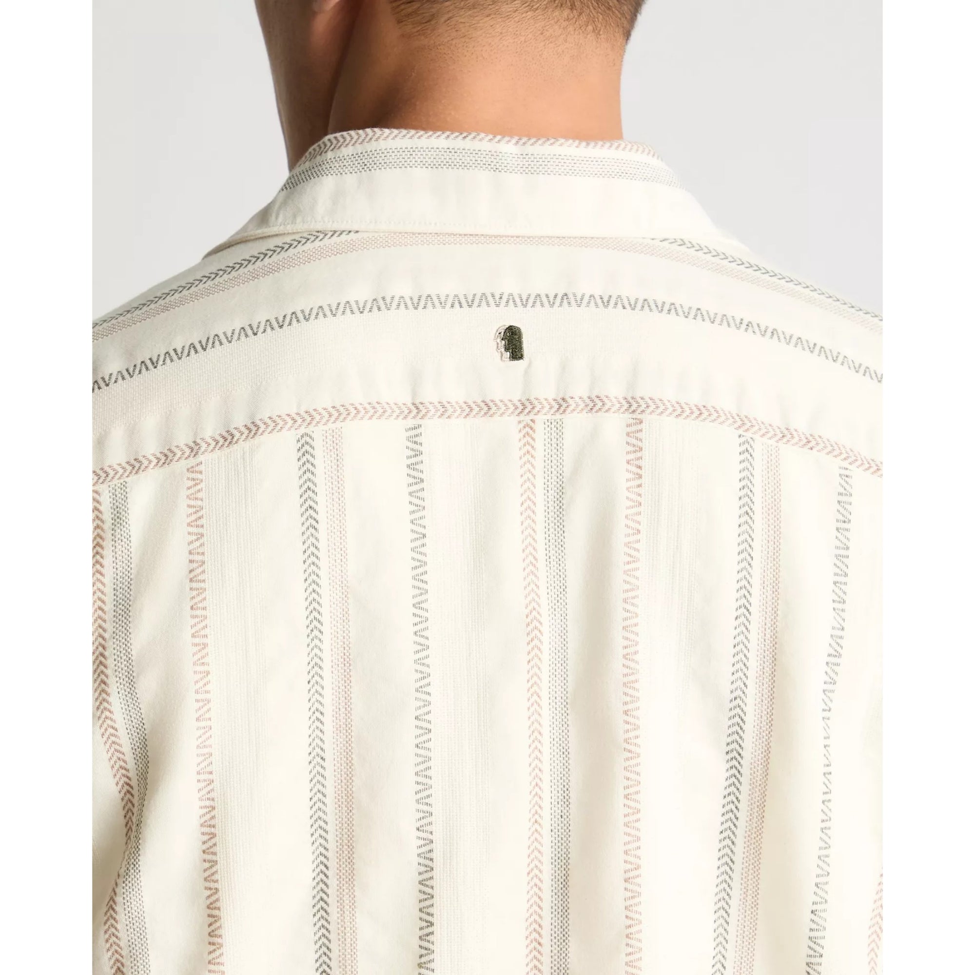 Close-up of a person wearing a light-colored shirt with subtle patterns on a plain background