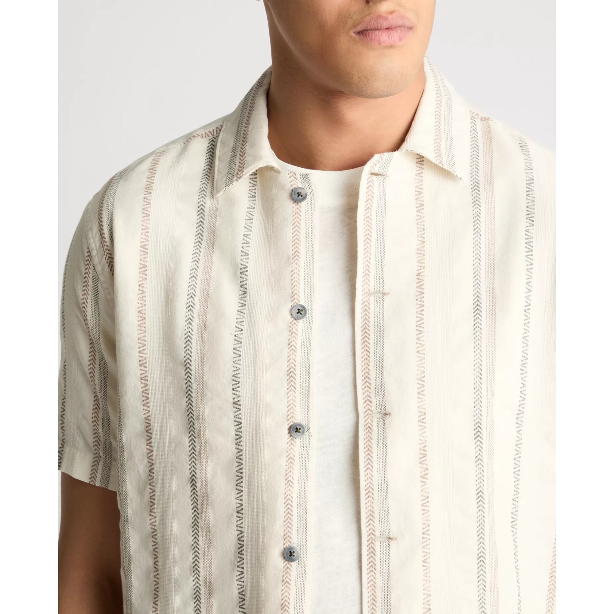 Man wearing a beige and brown striped shirt with a plain background