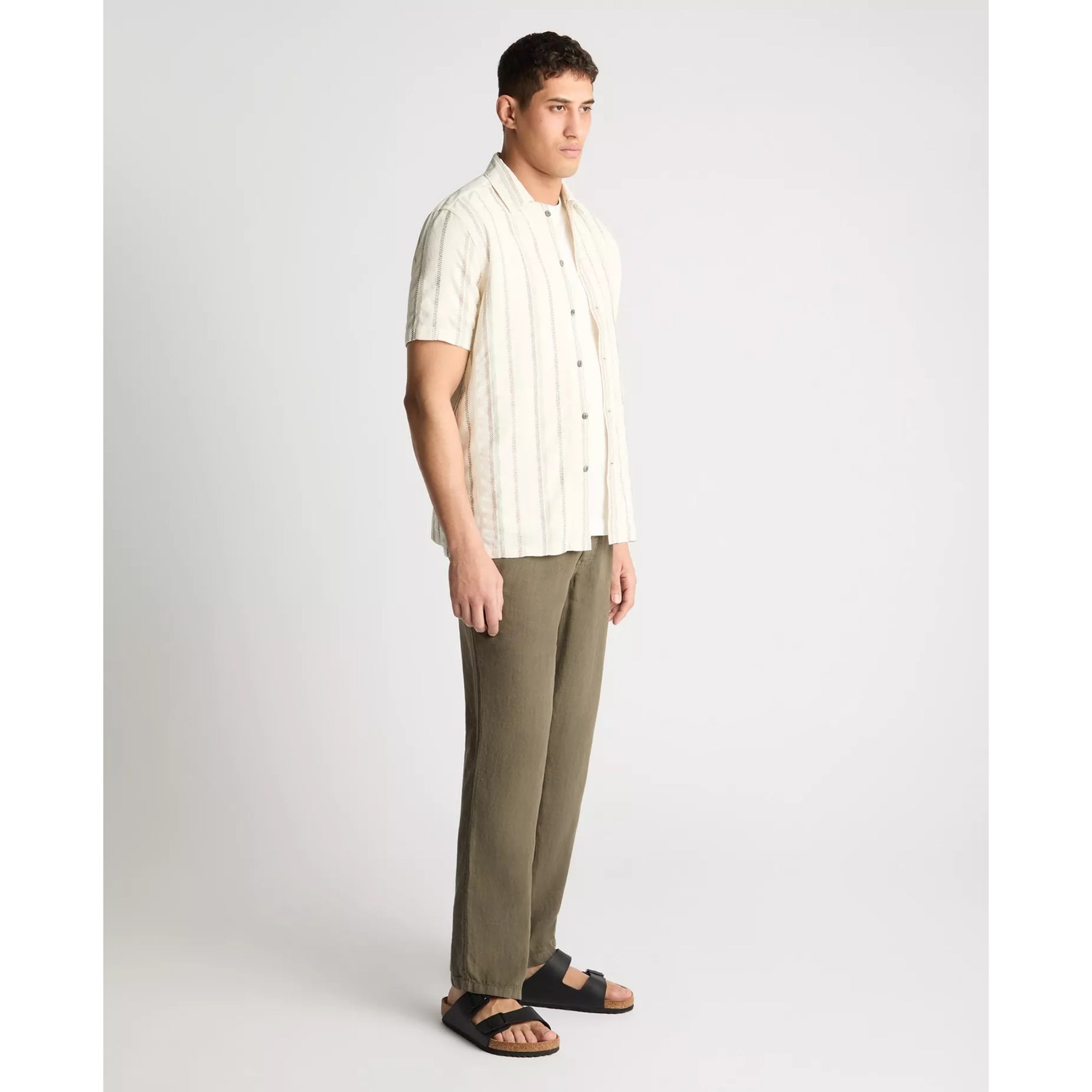 Man wearing a striped shirt and green pants on a white background