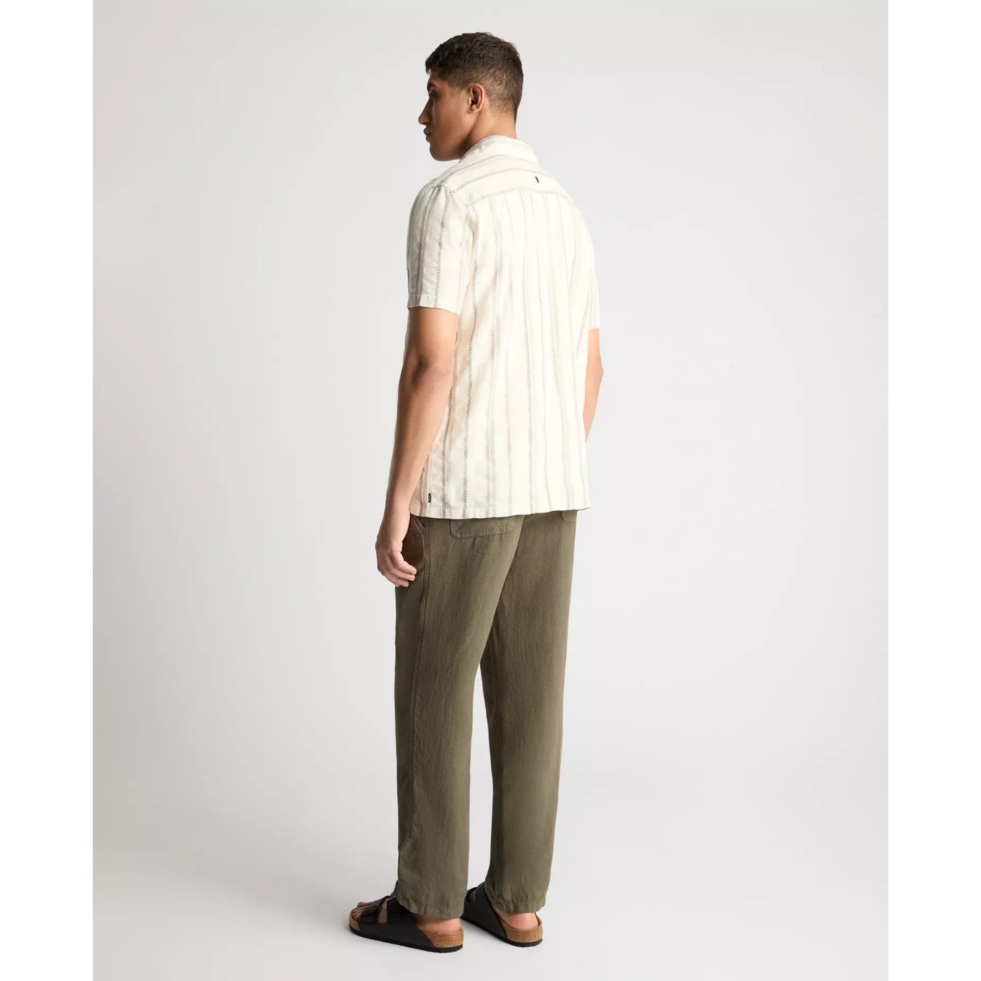 Man wearing a white striped shirt and green pants on a plain background