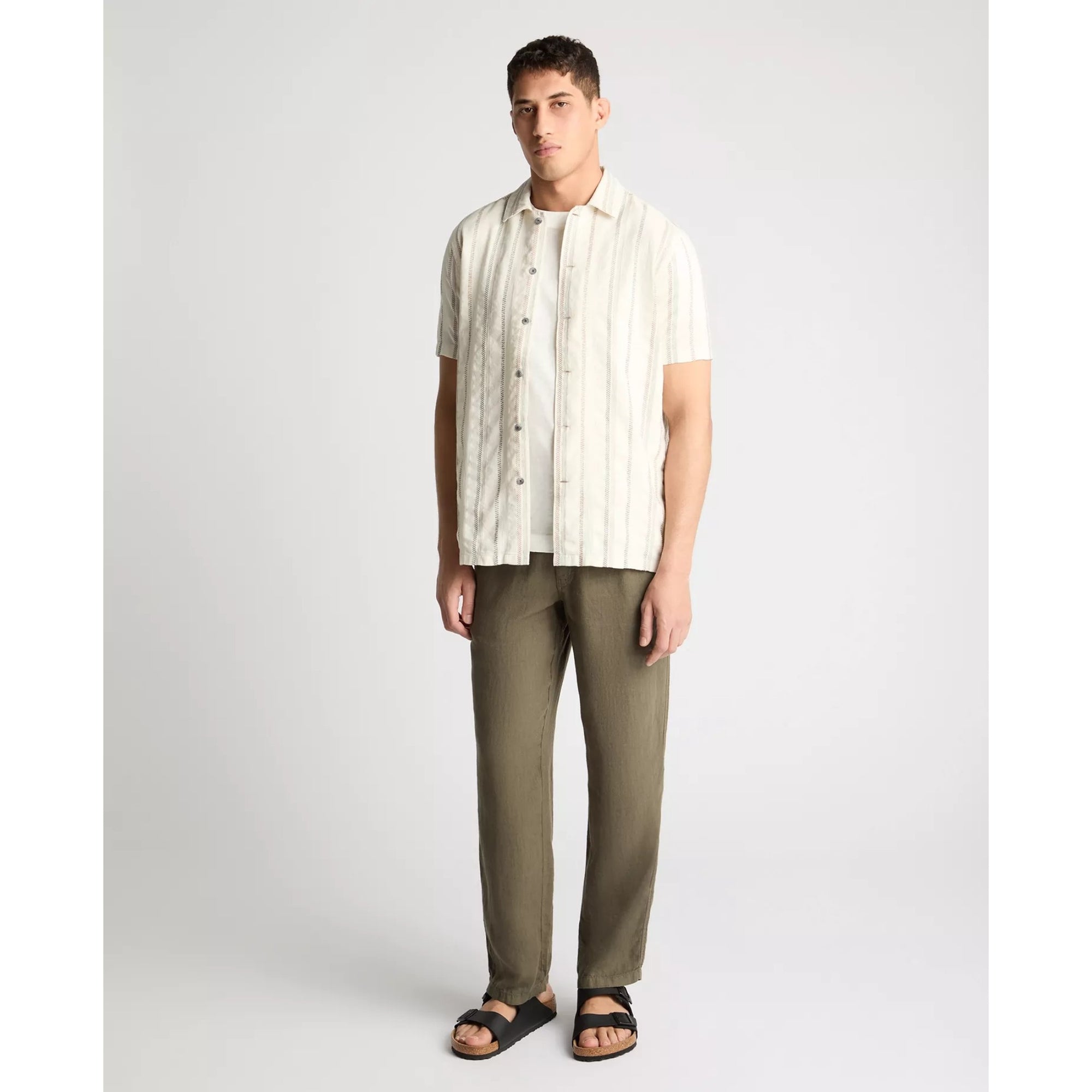 Man wearing a striped shirt and green pants on a white background