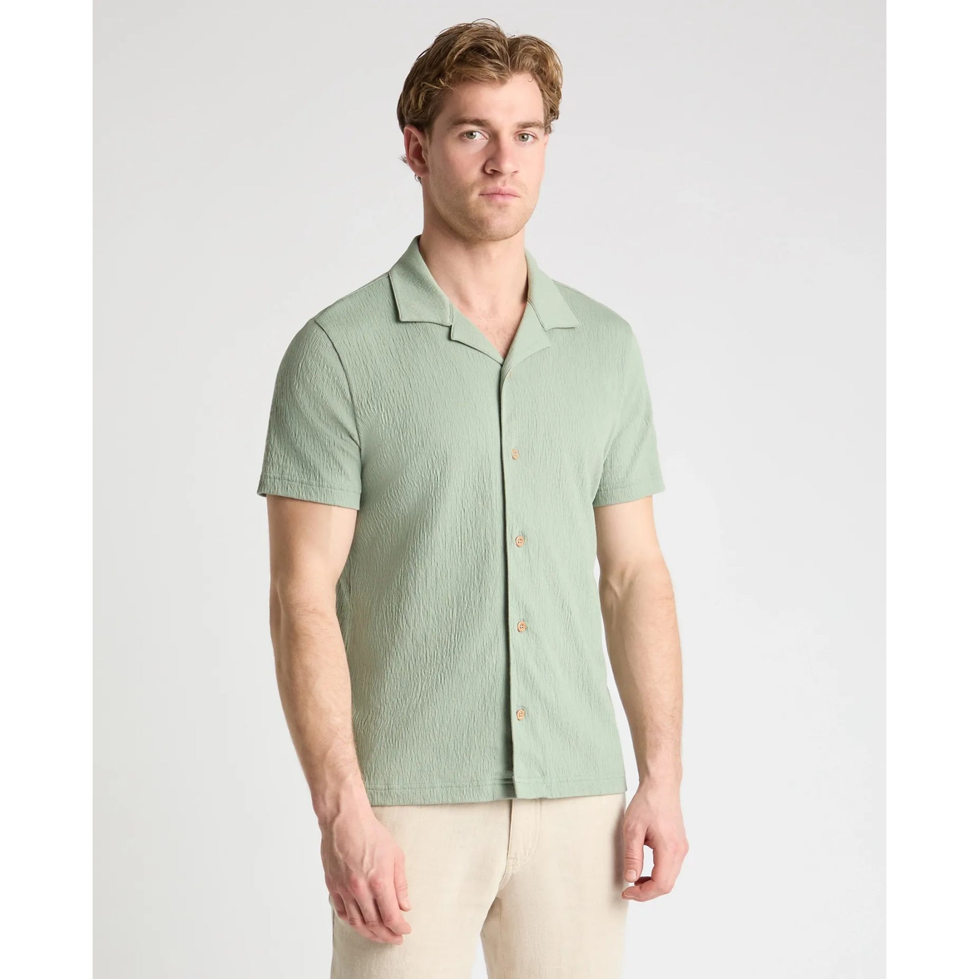 Man wearing a light green short-sleeve shirt on a white background