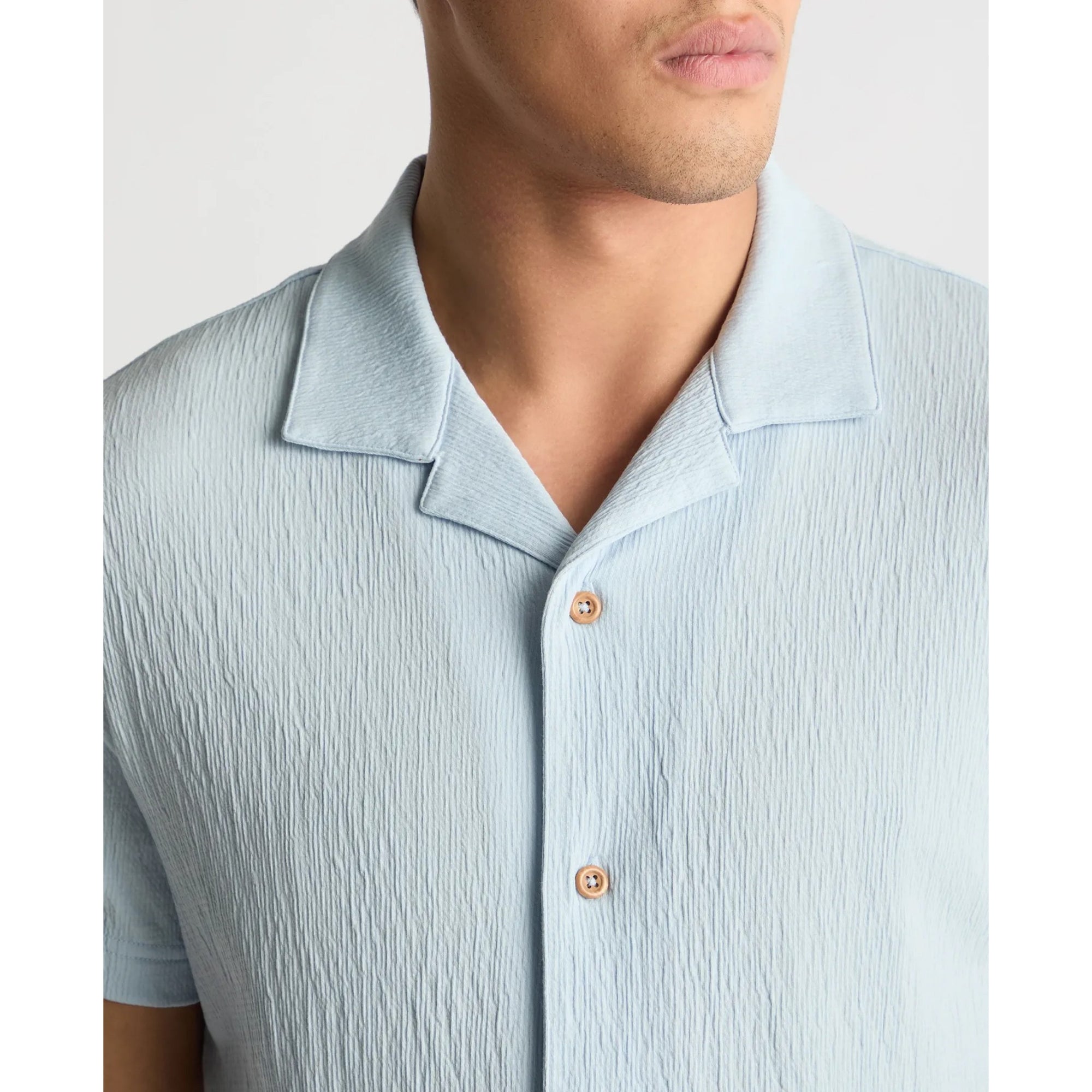 Light blue textured shirt worn by a person on a plain background