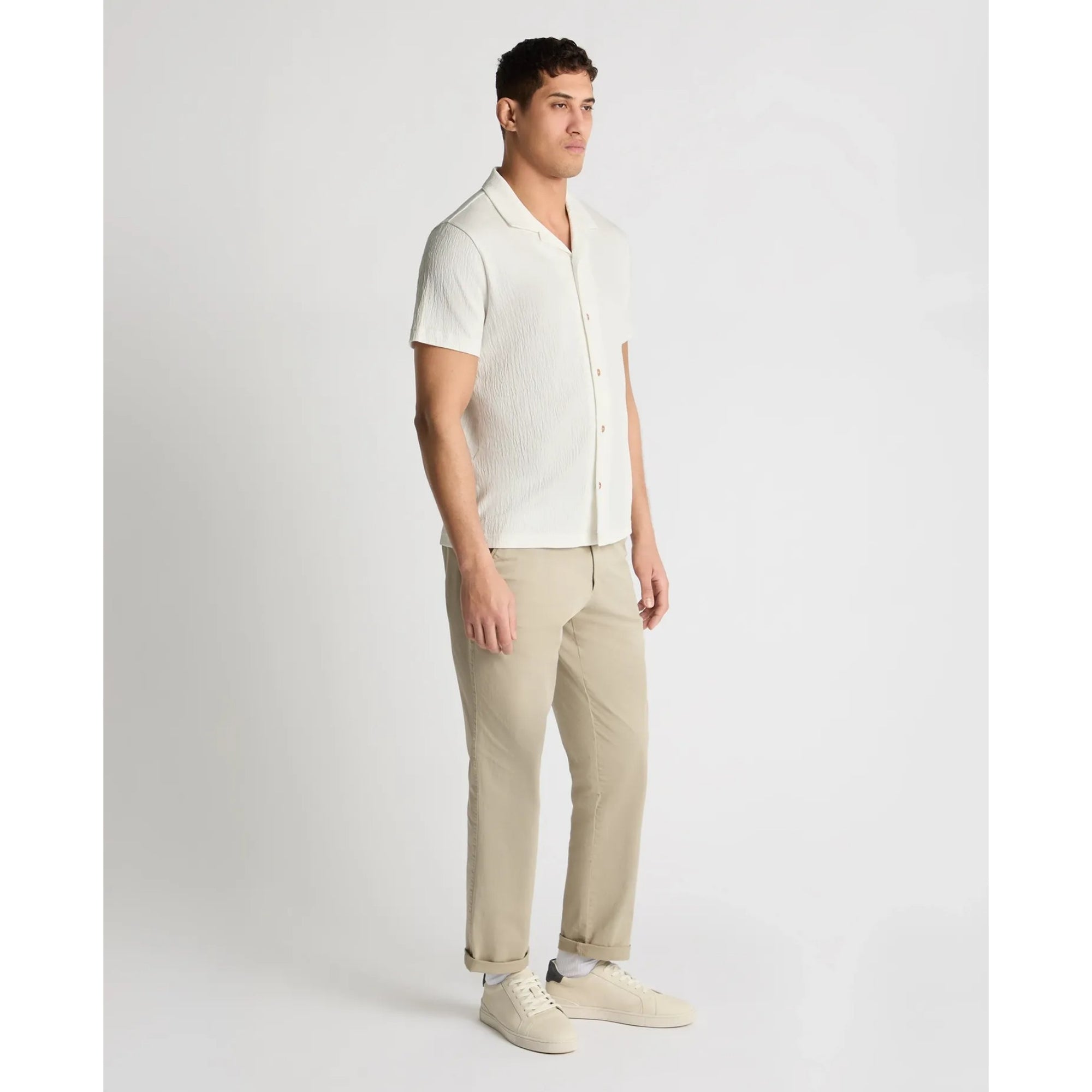 Man wearing a white shirt and beige pants on a light gray background