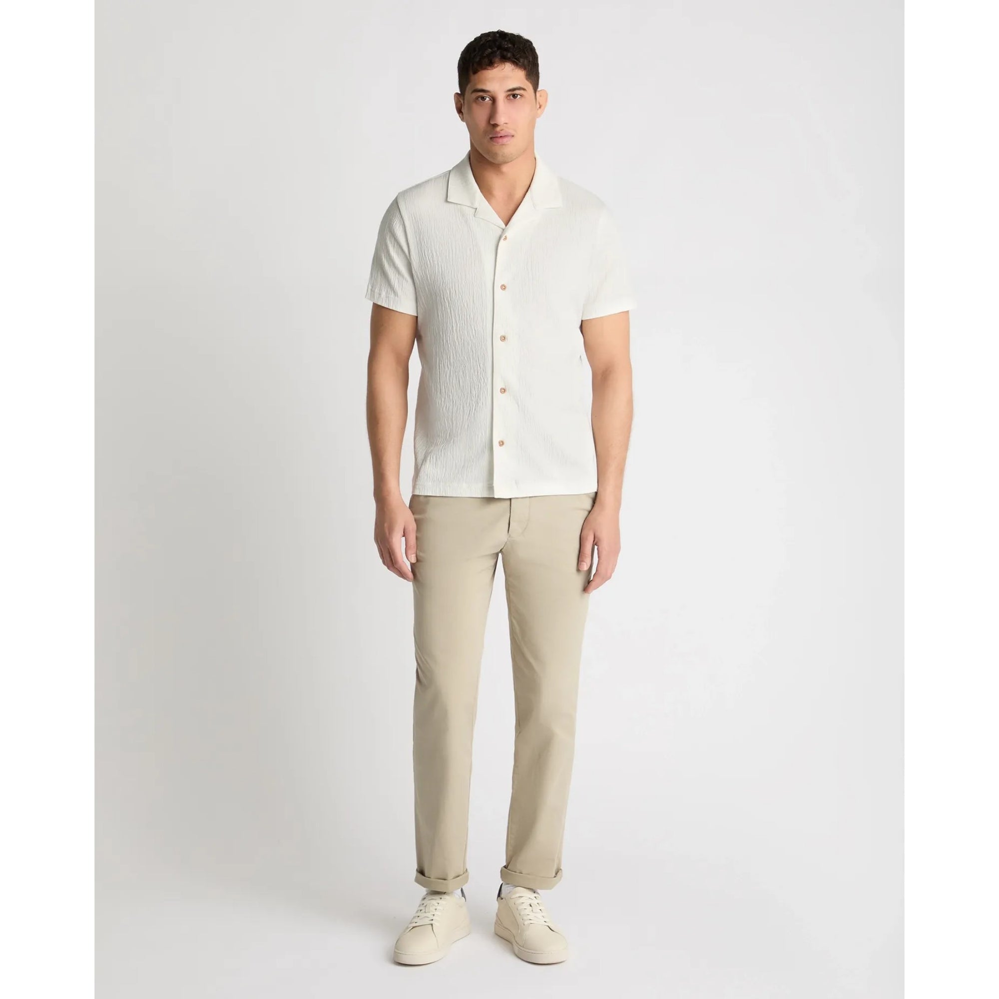 Man wearing a light-colored shirt and beige pants on a white background
