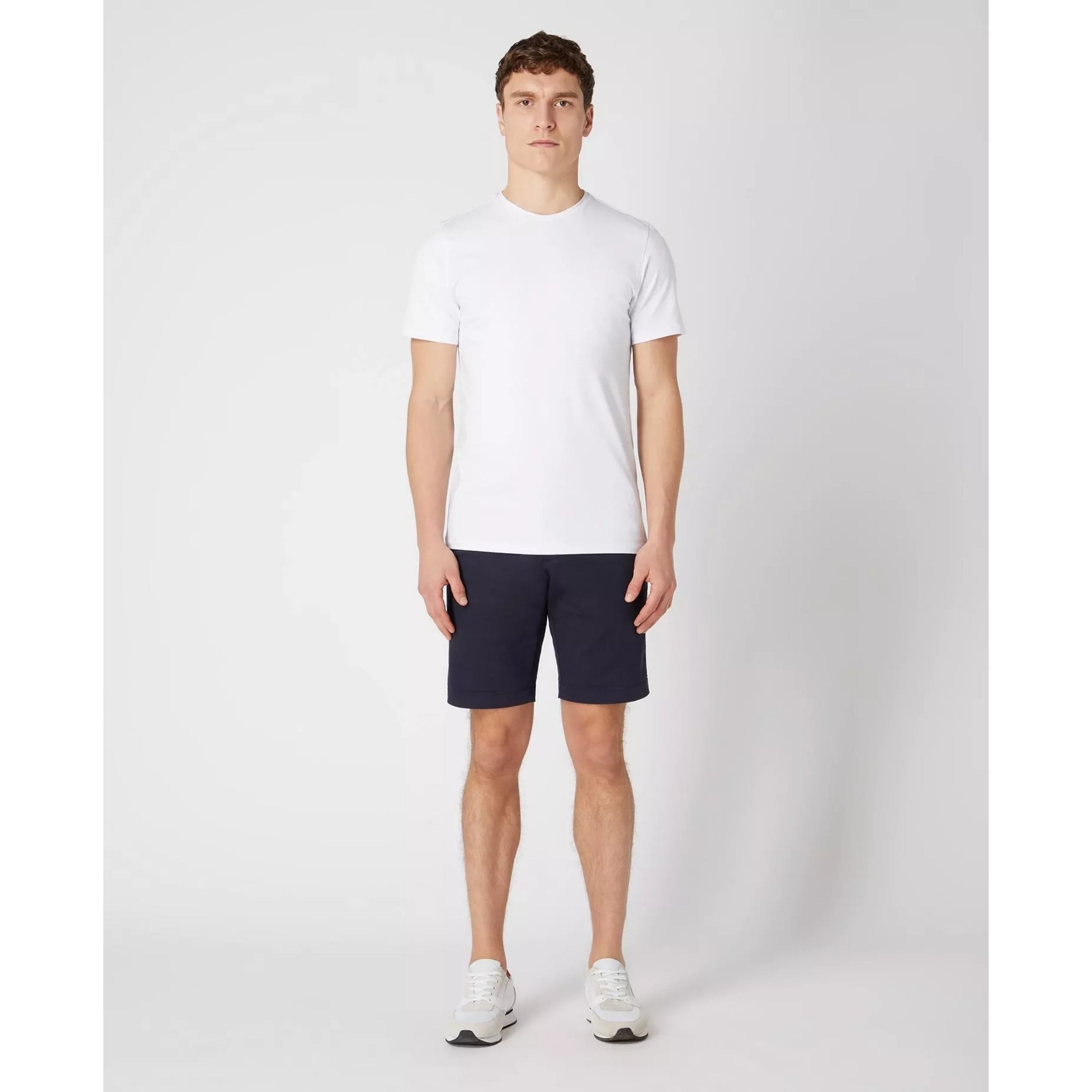 Man wearing a white t-shirt and navy shorts on a white background