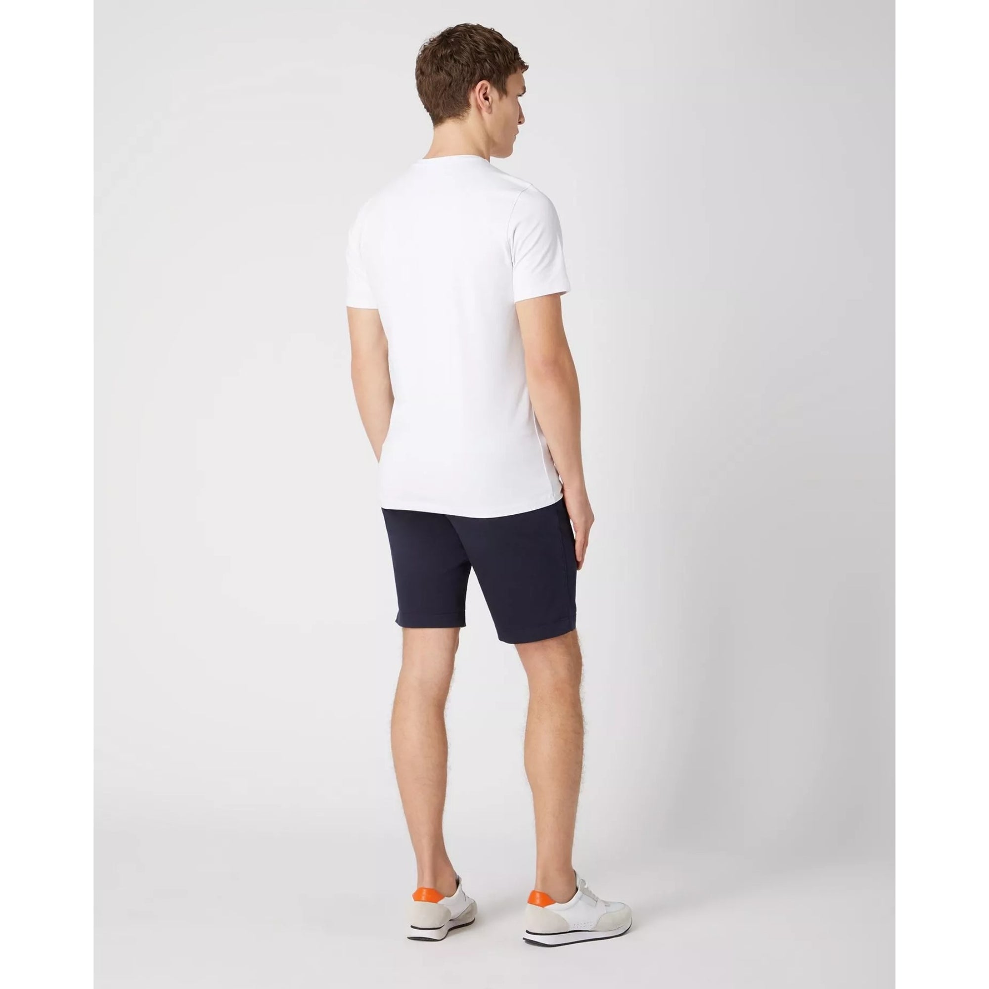 Man wearing a white t-shirt and navy shorts on a light gray background