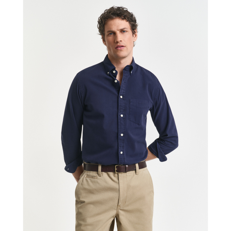 Man wearing a navy GANT button-up shirt and beige pants on a white background