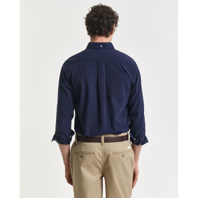 Man wearing a GANT navy shirt and beige pants on a white background