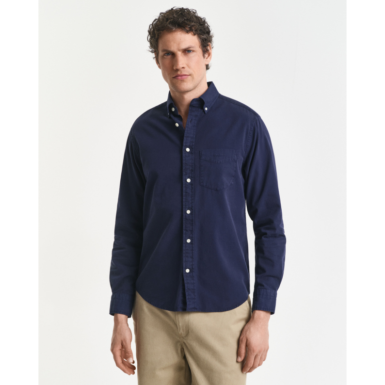 Man wearing a GANT navy button-up shirt and beige pants on a white background