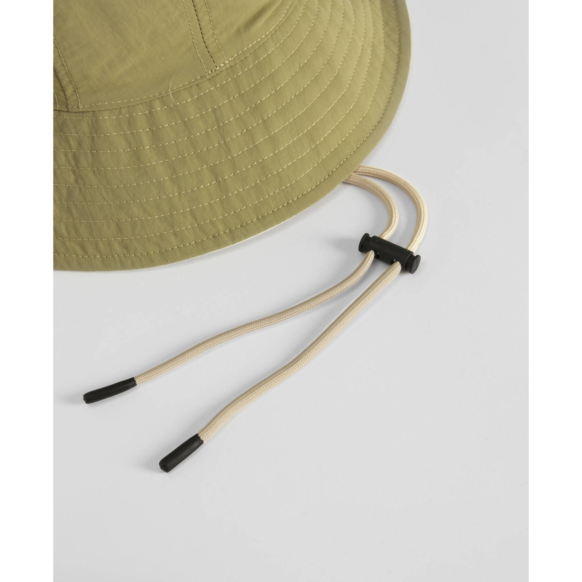 Green bucket hat with adjustable chin strap on a light gray background