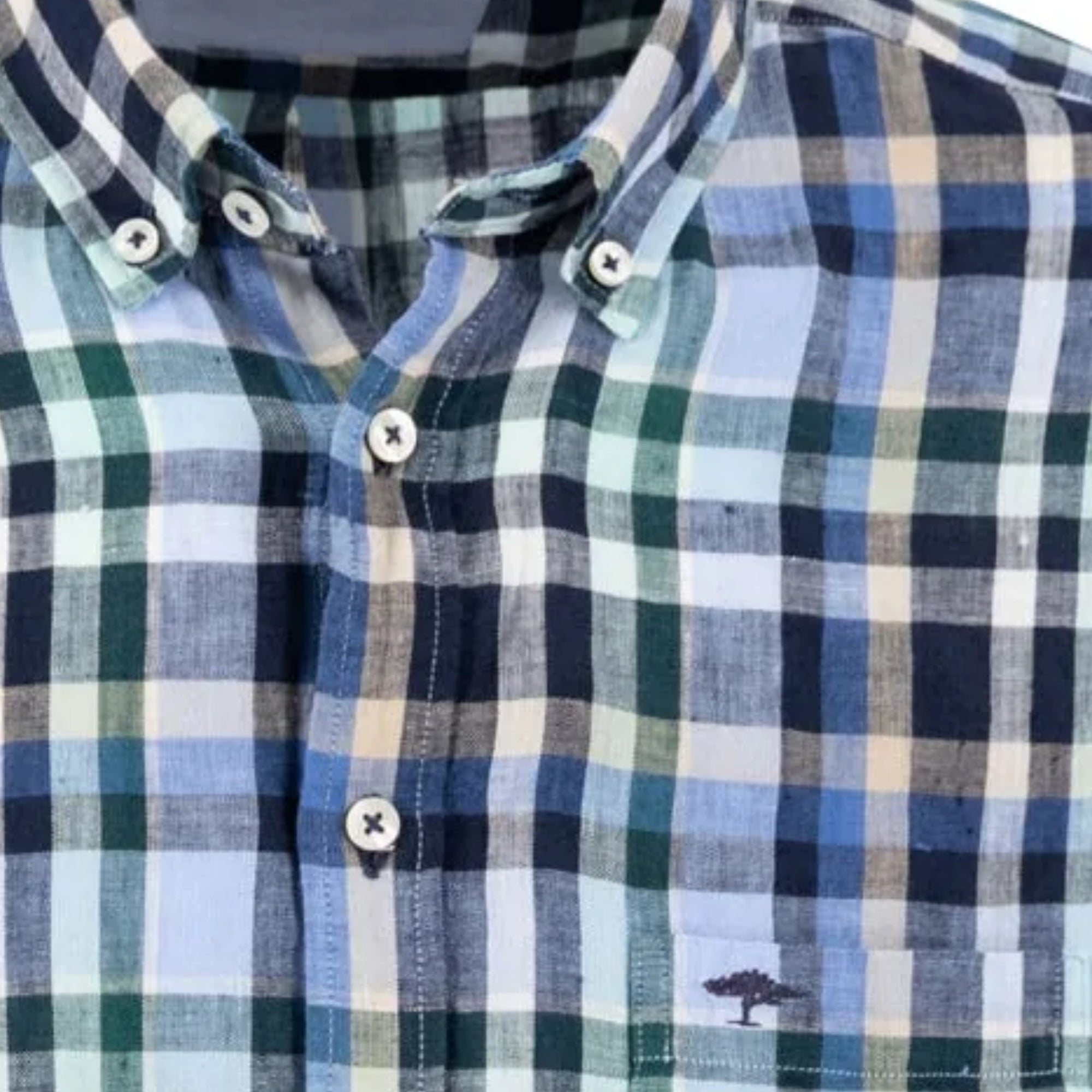 Close-up of a plaid shirt with a tree logo on the chest.