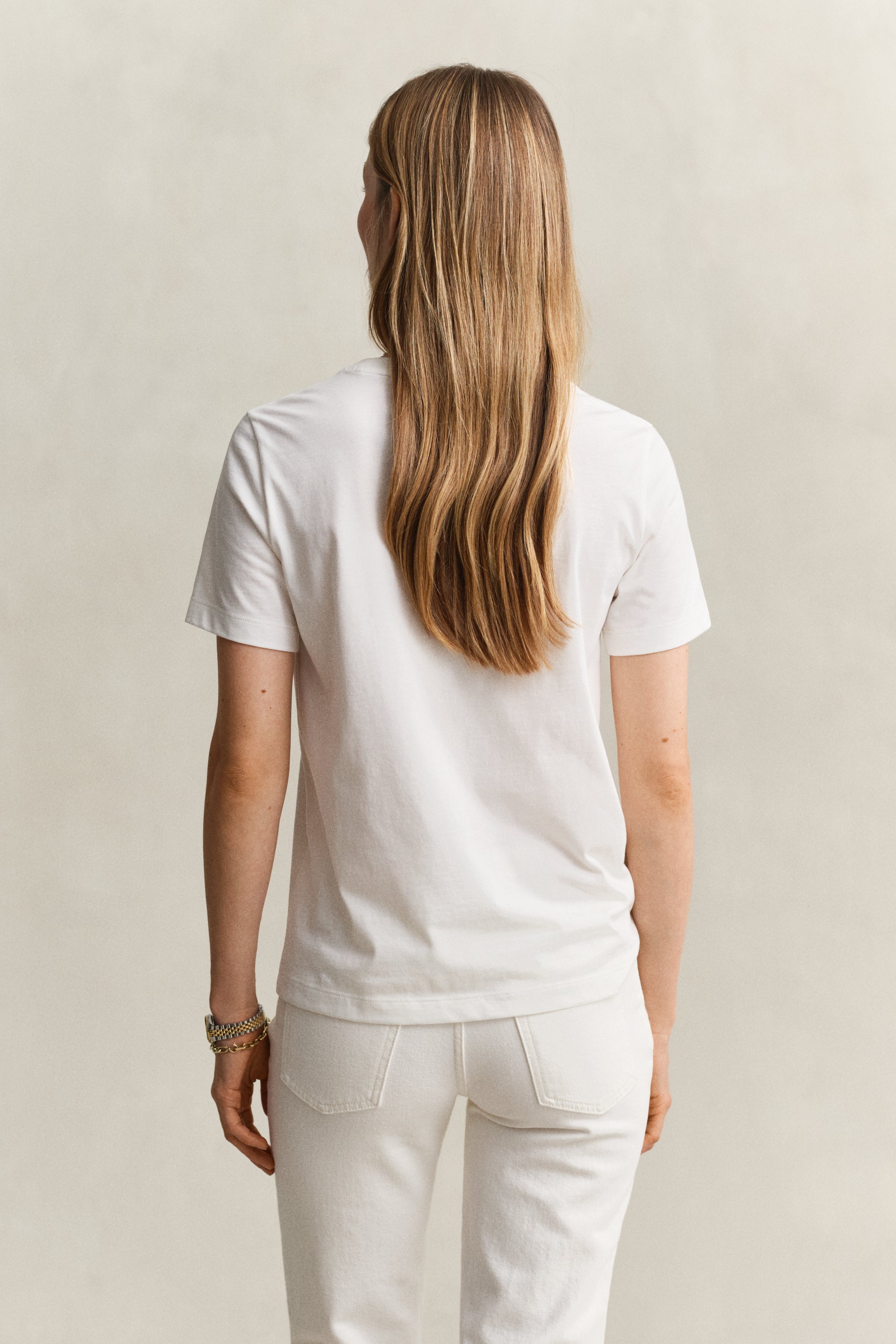 Person wearing a white t-shirt and light-colored pants against a neutral background