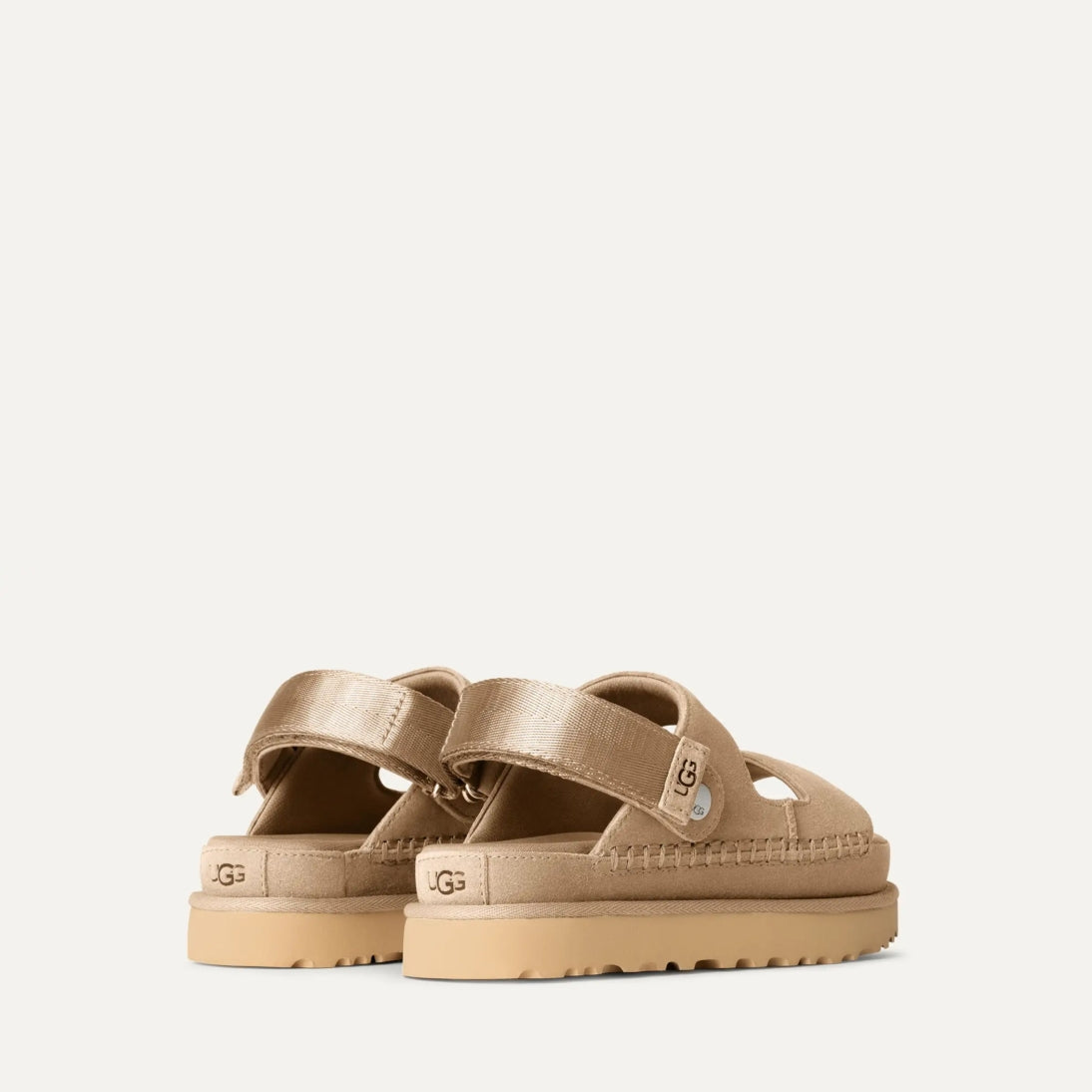 A pair of UGG Goldenstar Glide sandals in sand color with an adjustable heel strap and a low heel.