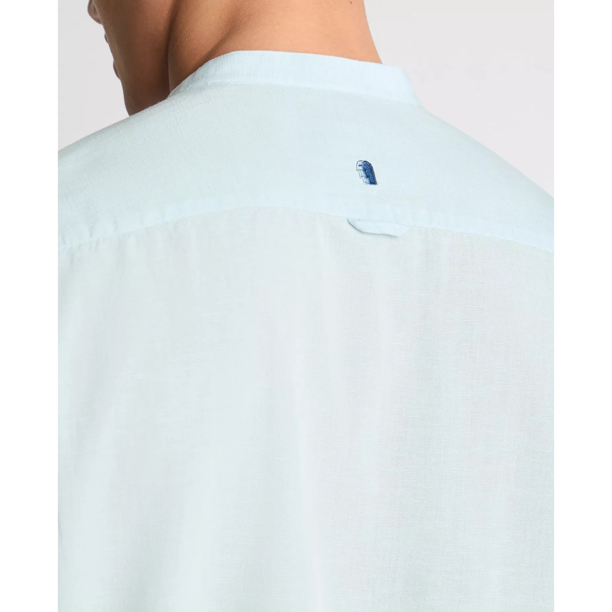Light blue shirt with a small logo on the chest pocket against a white background