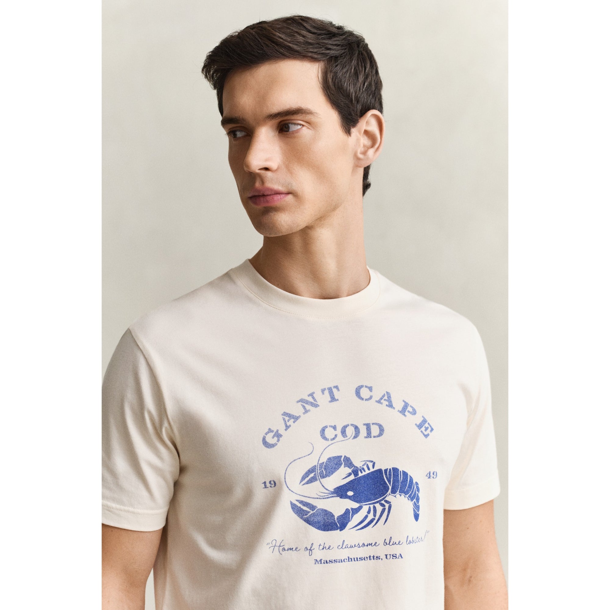 Man wearing a white t-shirt with blue graphic and text on a plain background