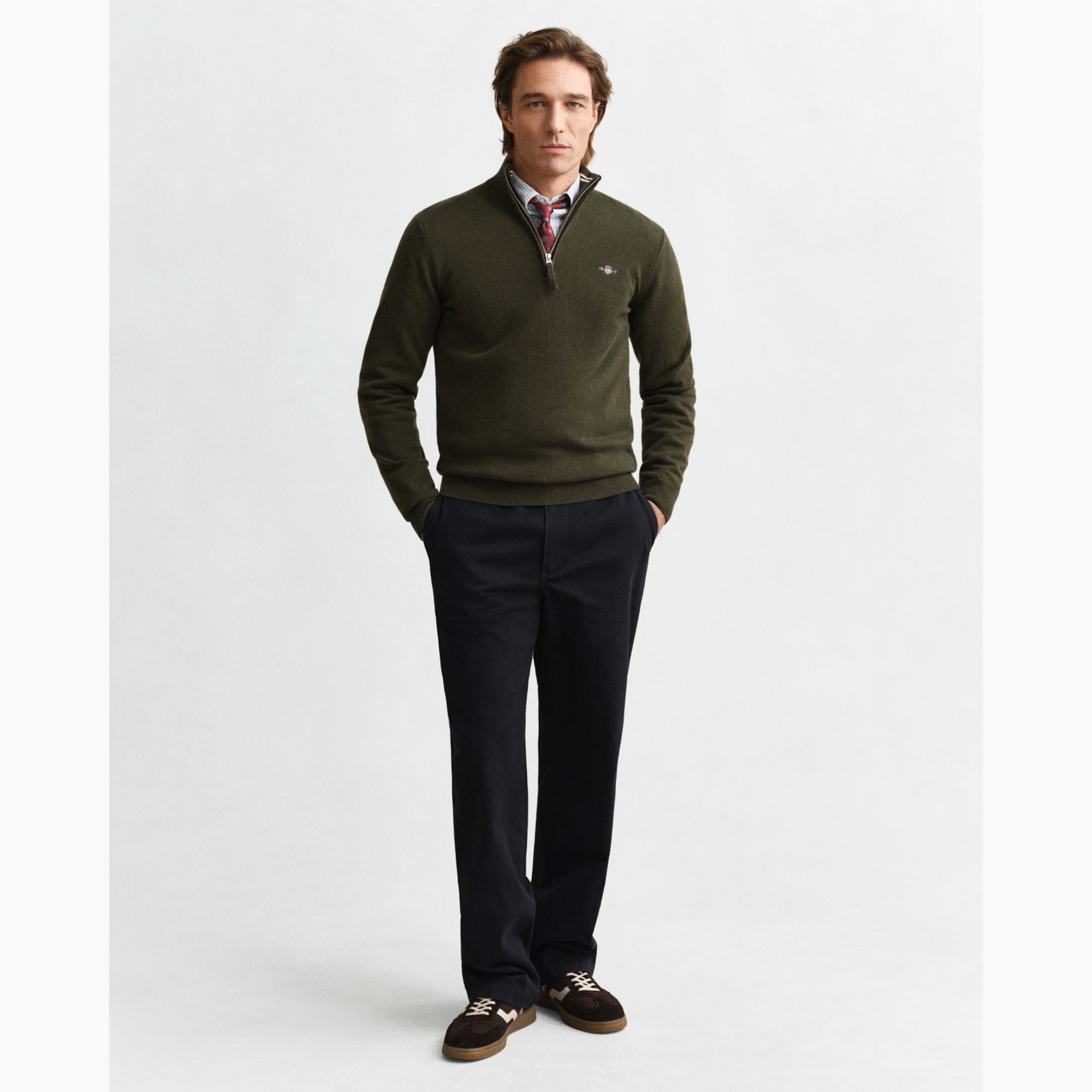 Man wearing a green GANT sweater and black pants