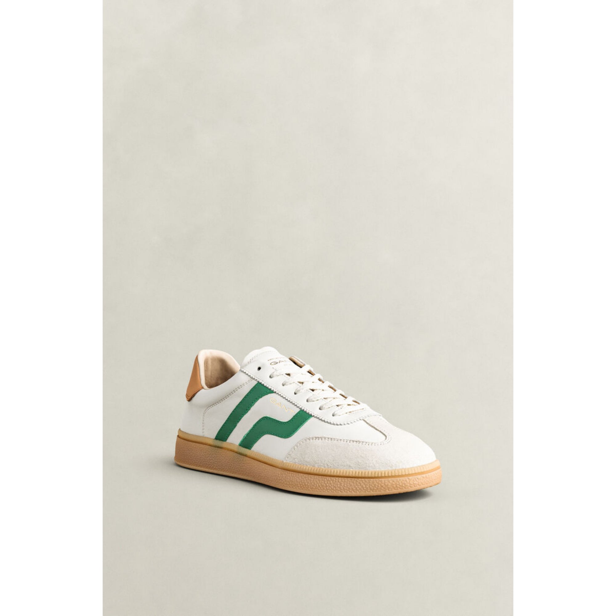 White sneaker with green logo on a light gray background