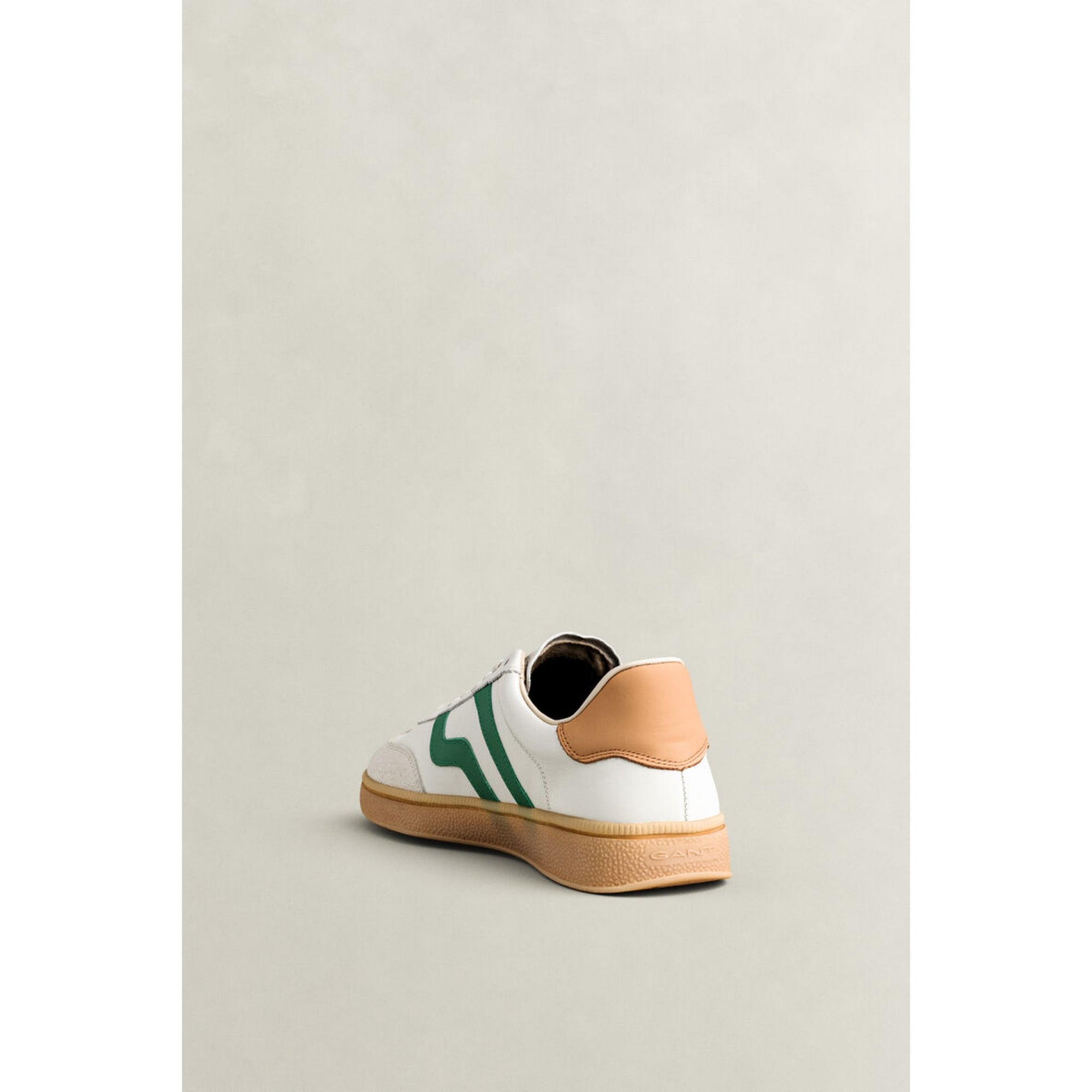 White sneaker with green stripes and tan heel on a light gray background