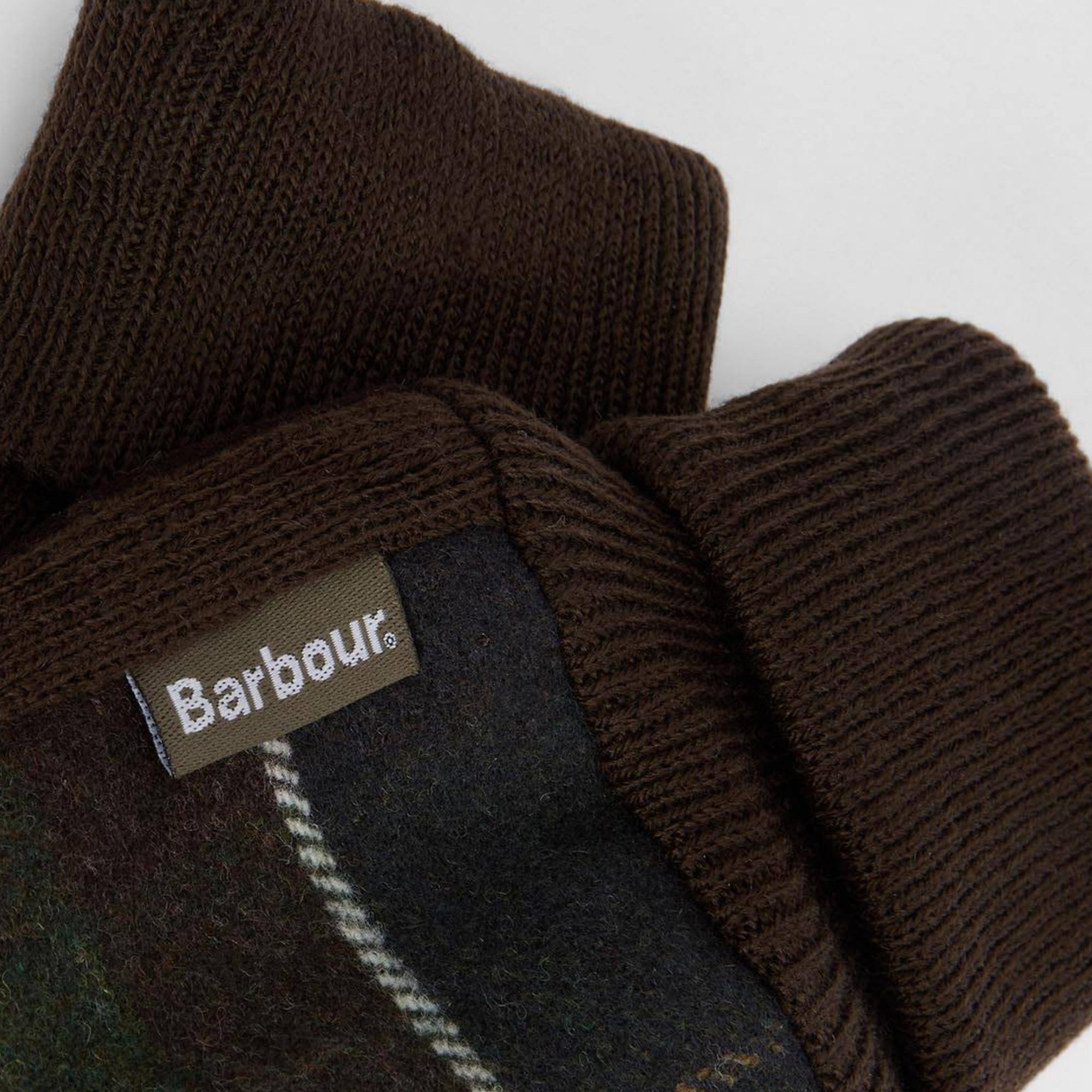 Close-up of a Barbour branded label on a brown fabric with plaid pattern.
