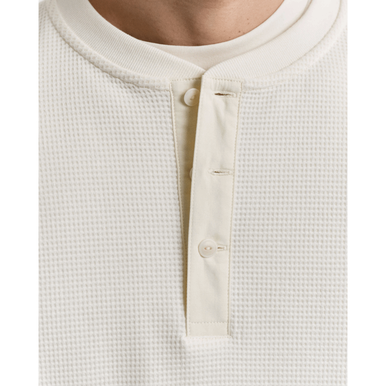 Close-up of a textured white garment with buttons on a white background