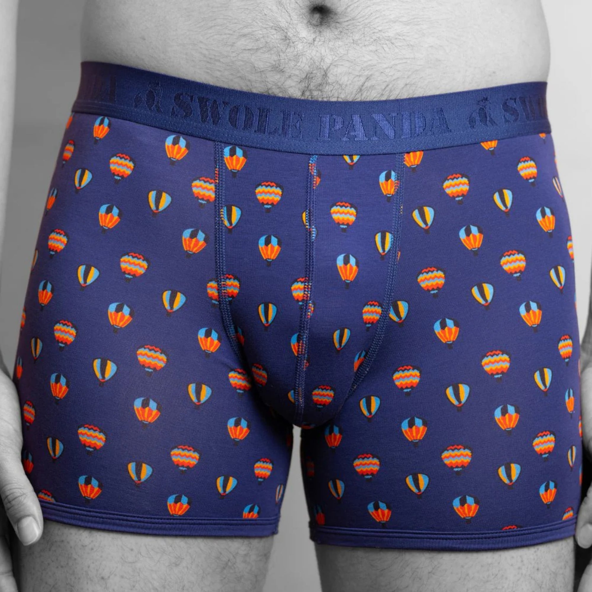 Blue boxer briefs with colorful hot air balloon pattern worn by a person.