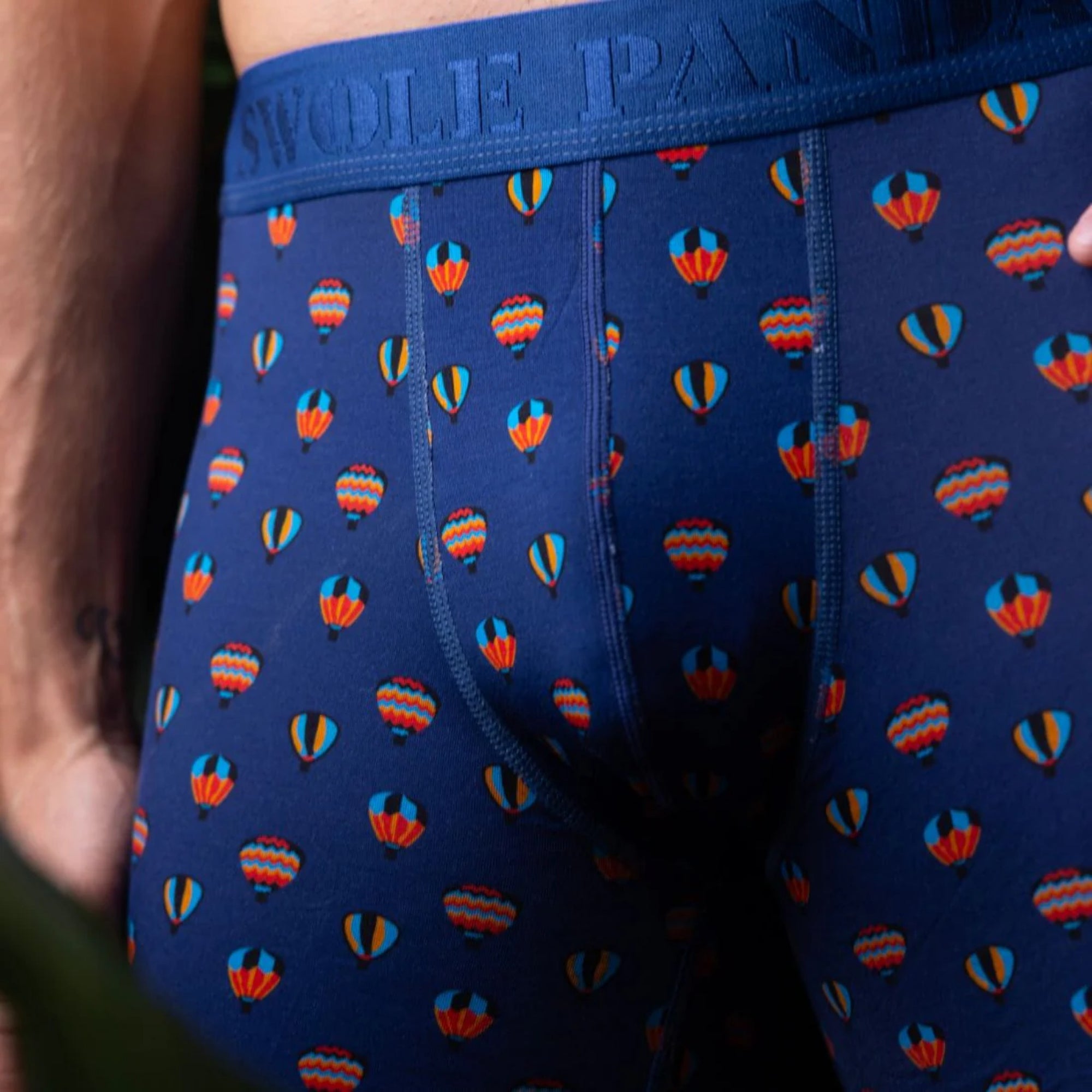 Navy boxer briefs with colorful hot air balloon pattern worn by a person.