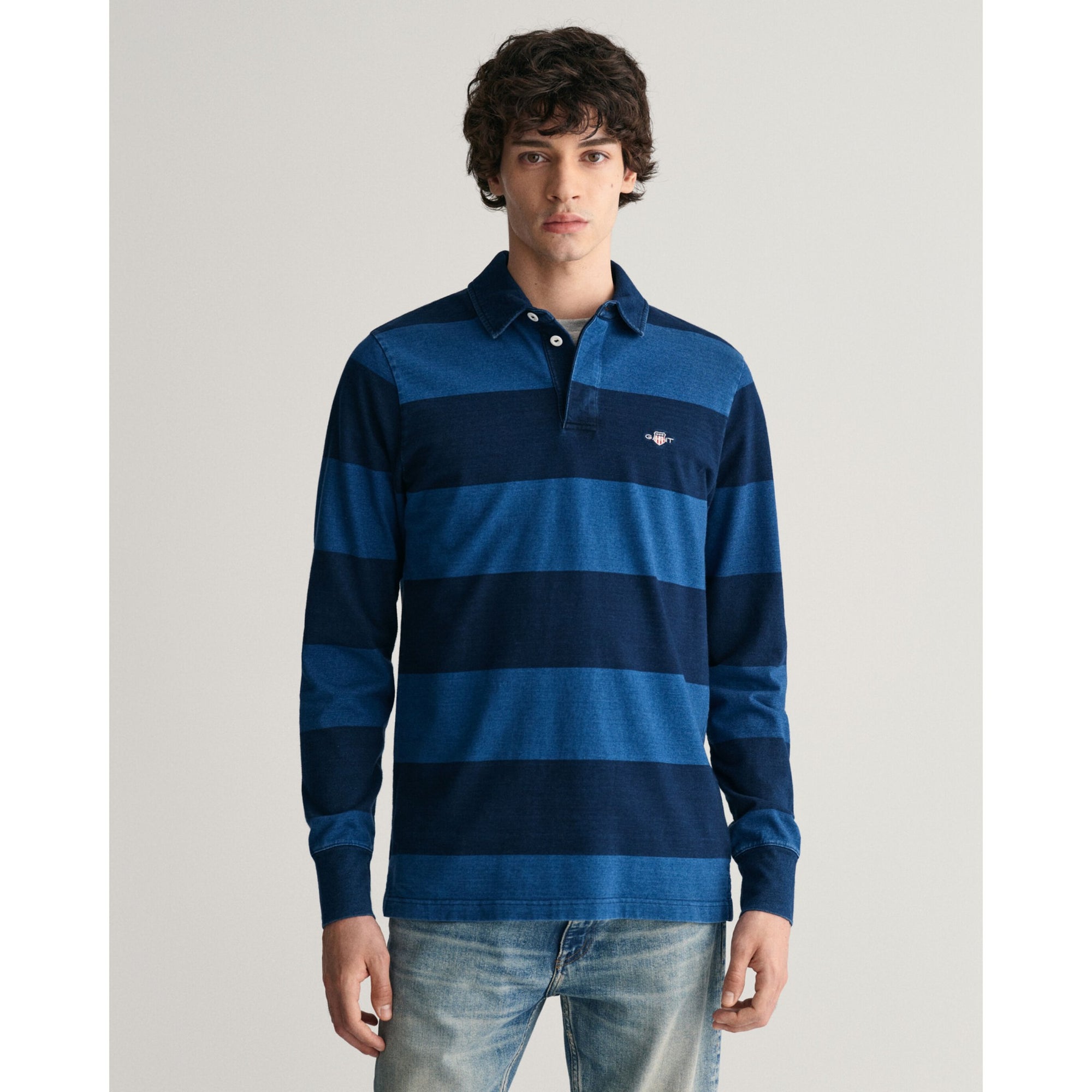 Man wearing a blue striped long-sleeve polo shirt on a light gray background