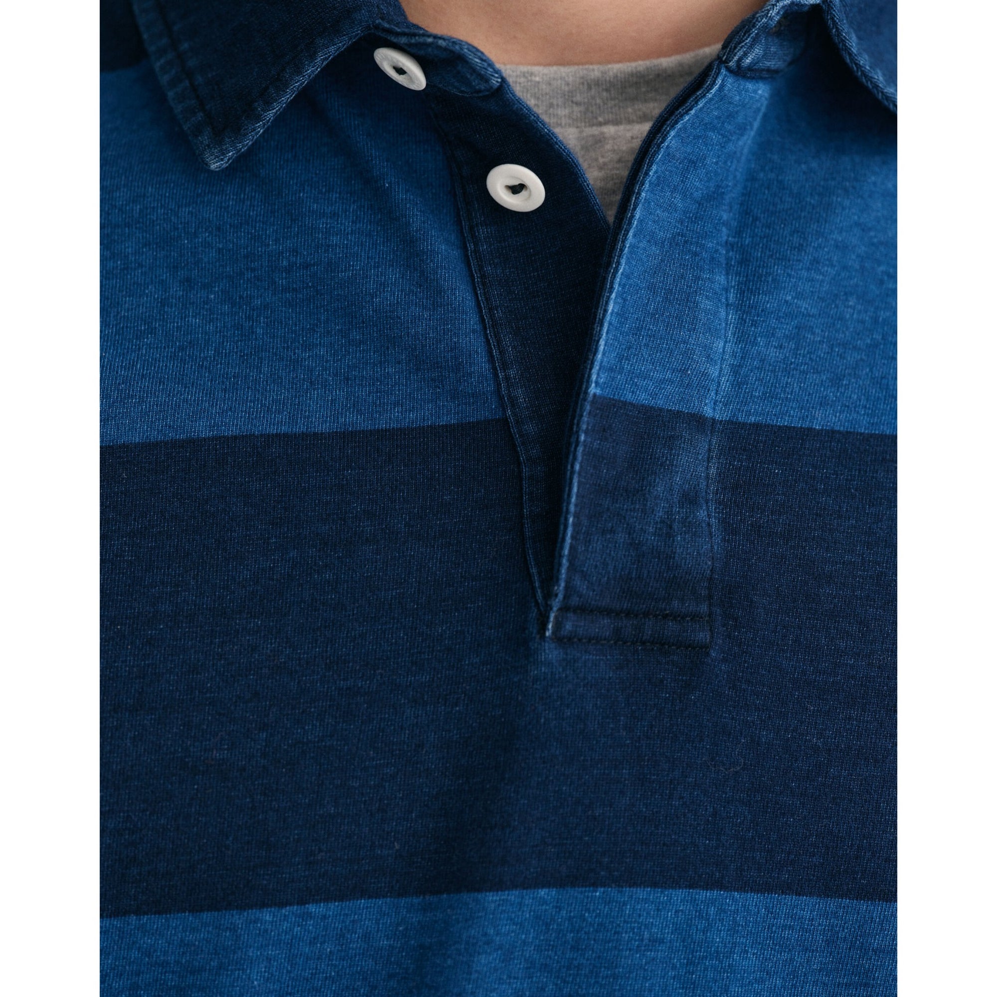 Close-up of a blue polo shirt with white buttons on a white background