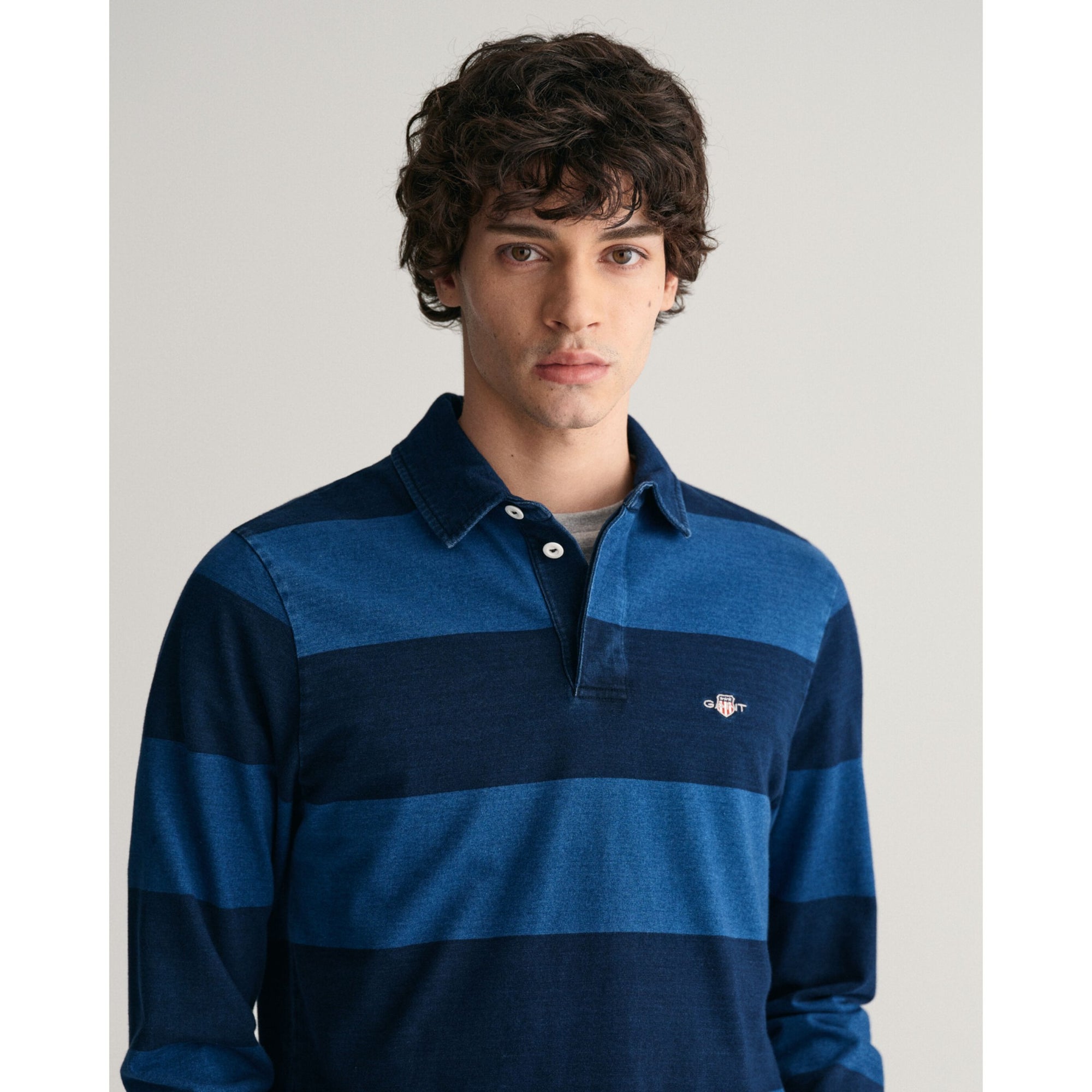 Man wearing a blue striped polo shirt against a plain background