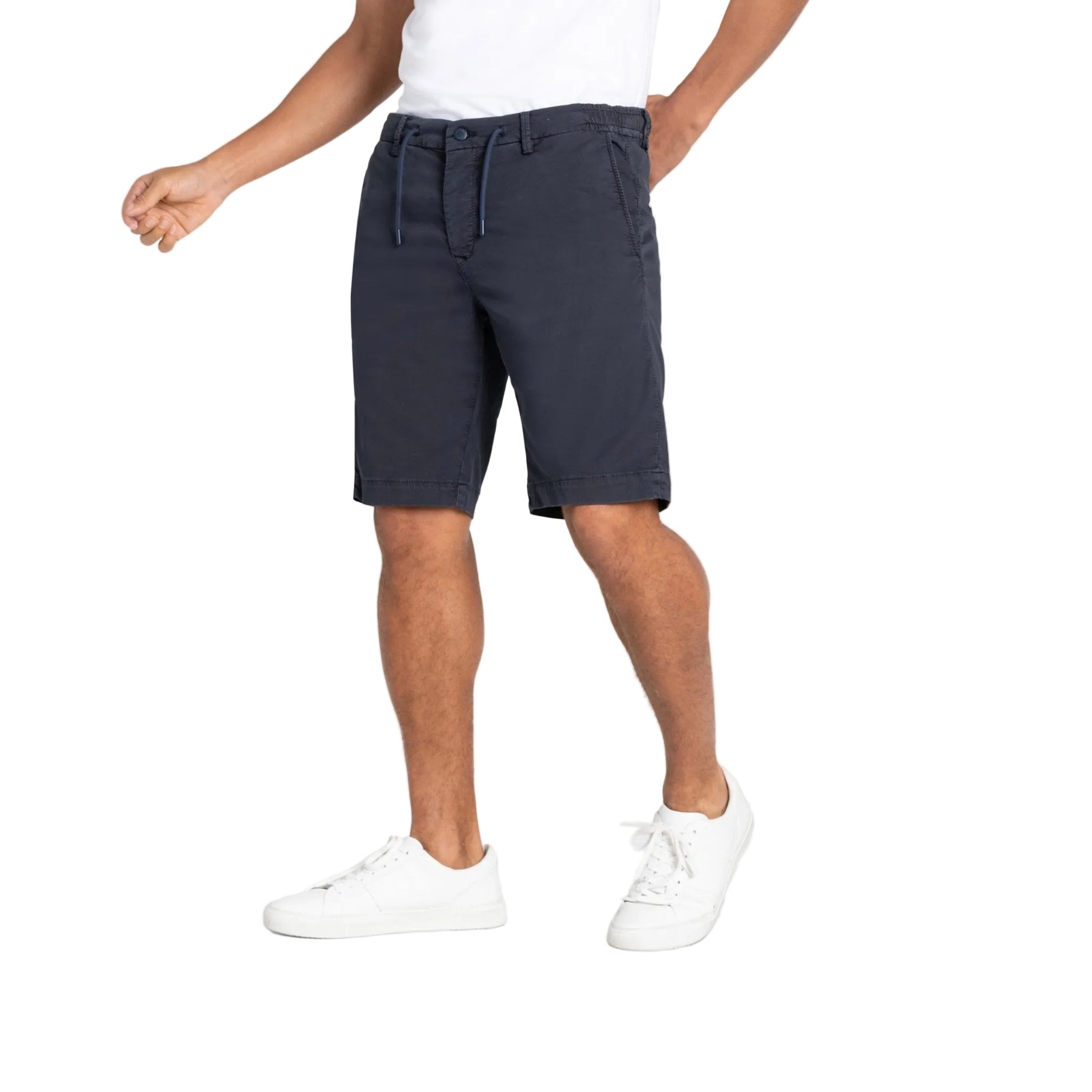 Person wearing navy shorts and white sneakers on a light gray background