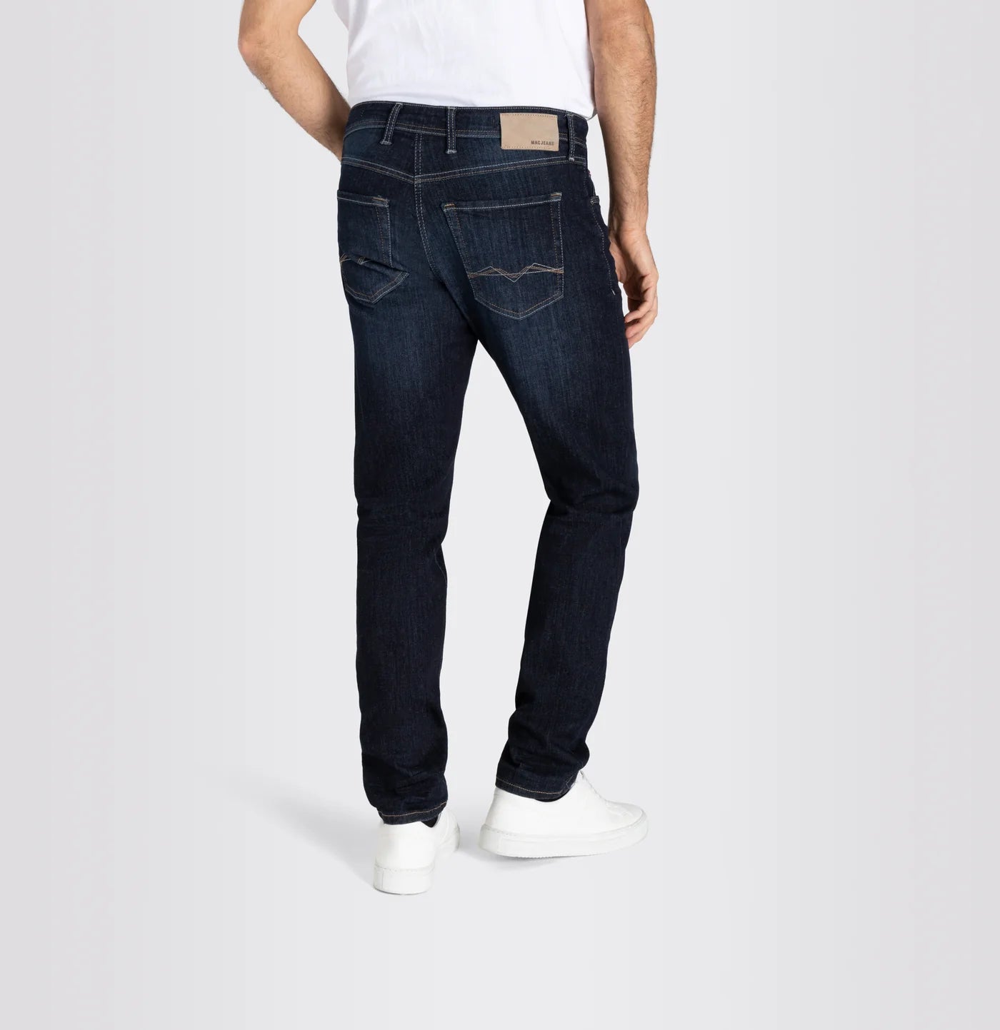 Person wearing dark blue jeans on a white background