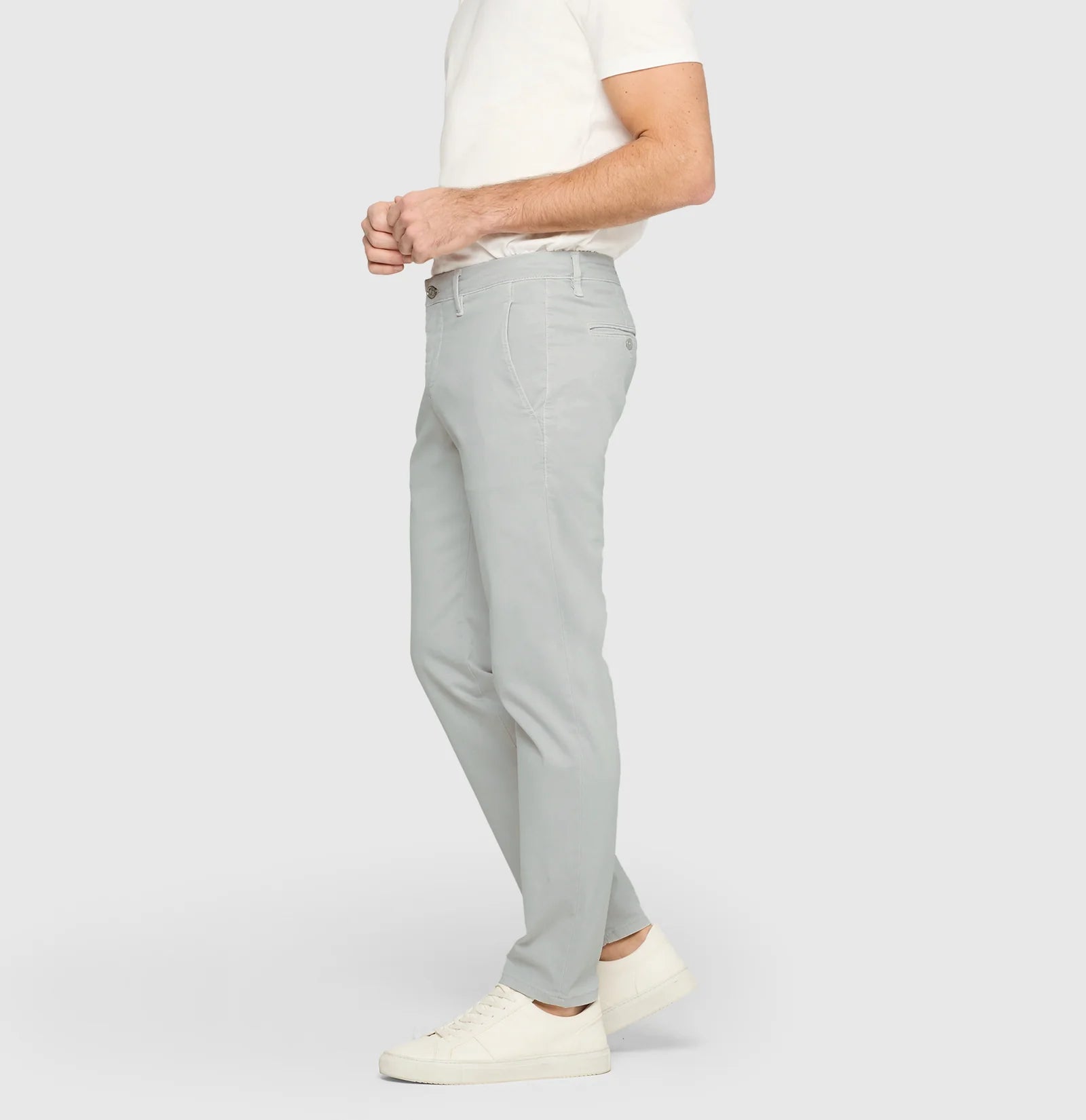 Person wearing light gray pants and a white shirt on a plain background