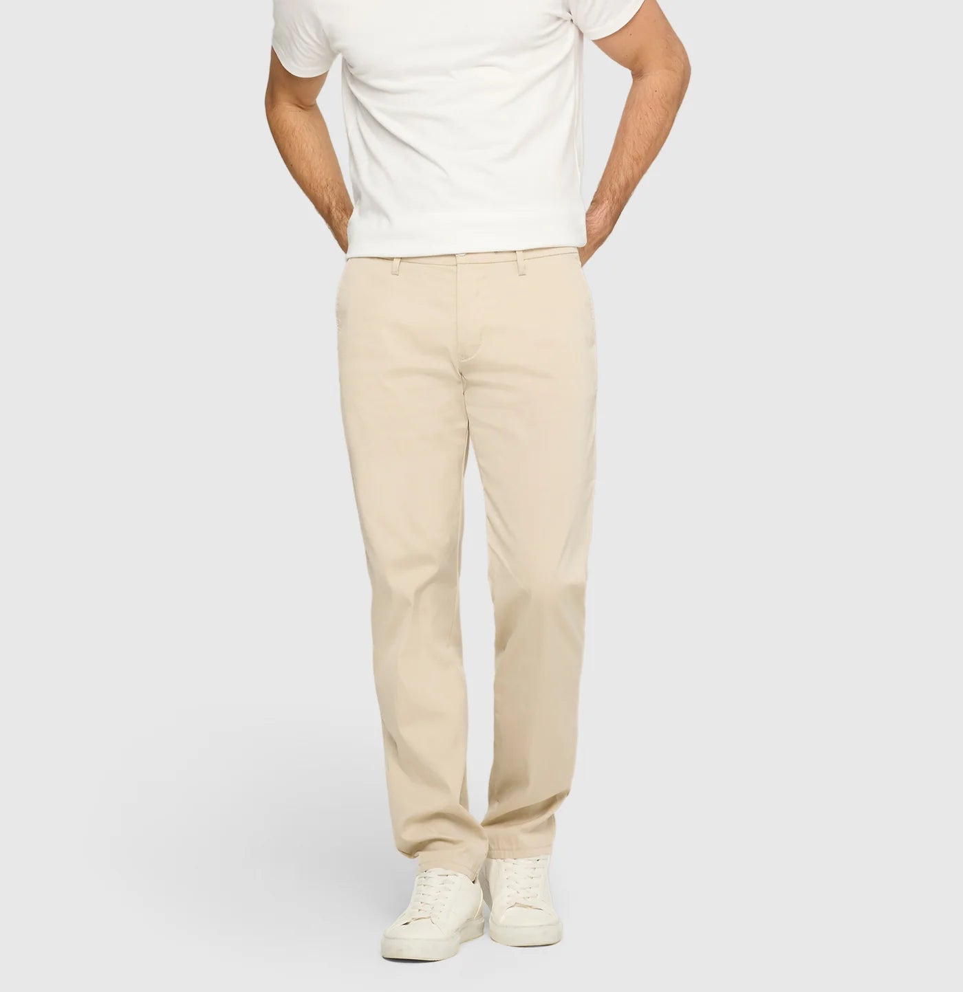 Person wearing a white t-shirt and beige pants on a plain background