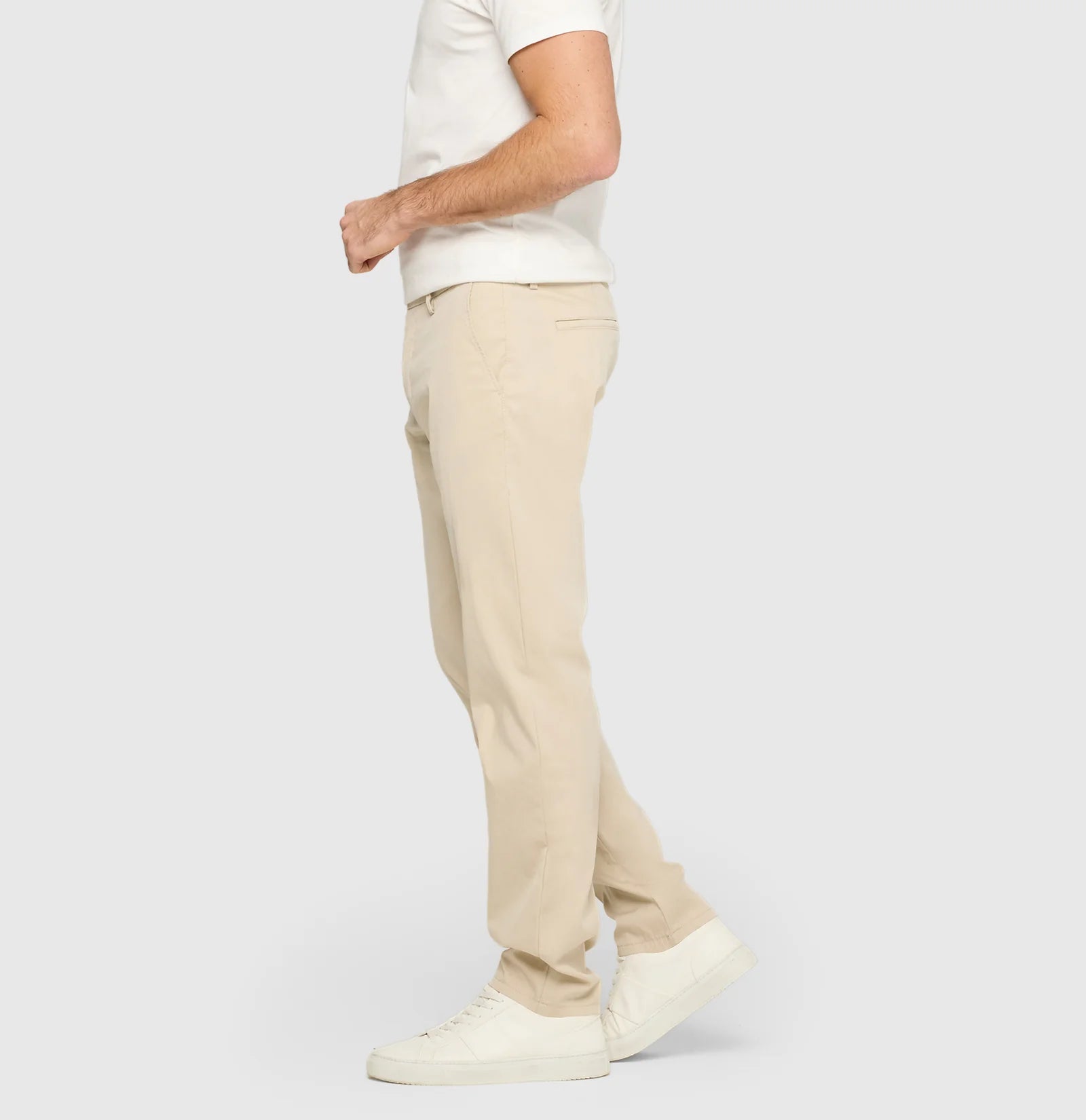 Person wearing beige pants and a white shirt on a light gray background