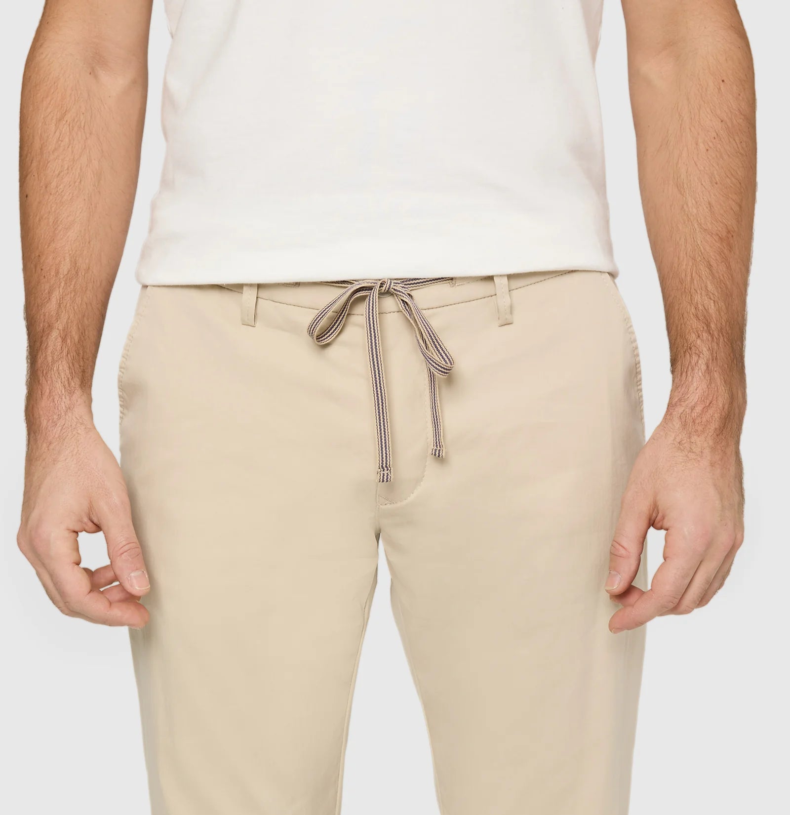 Beige pants with a drawstring worn by a person on a light gray background