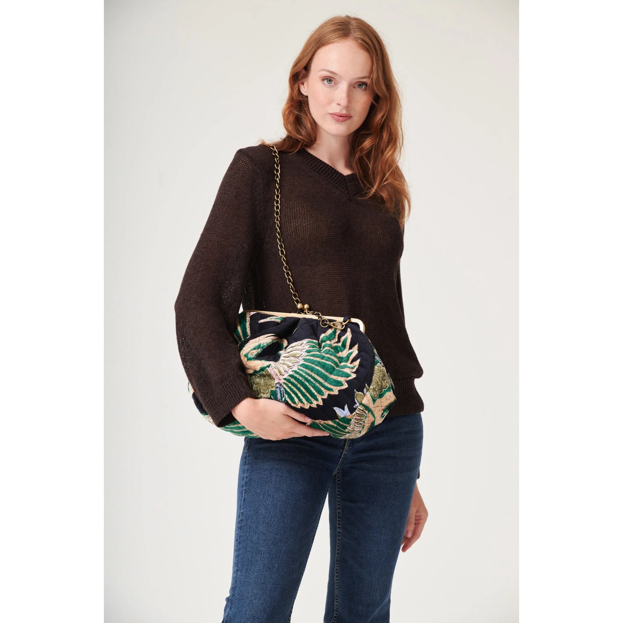 Woman holding a decorative clutch bag with a plain background