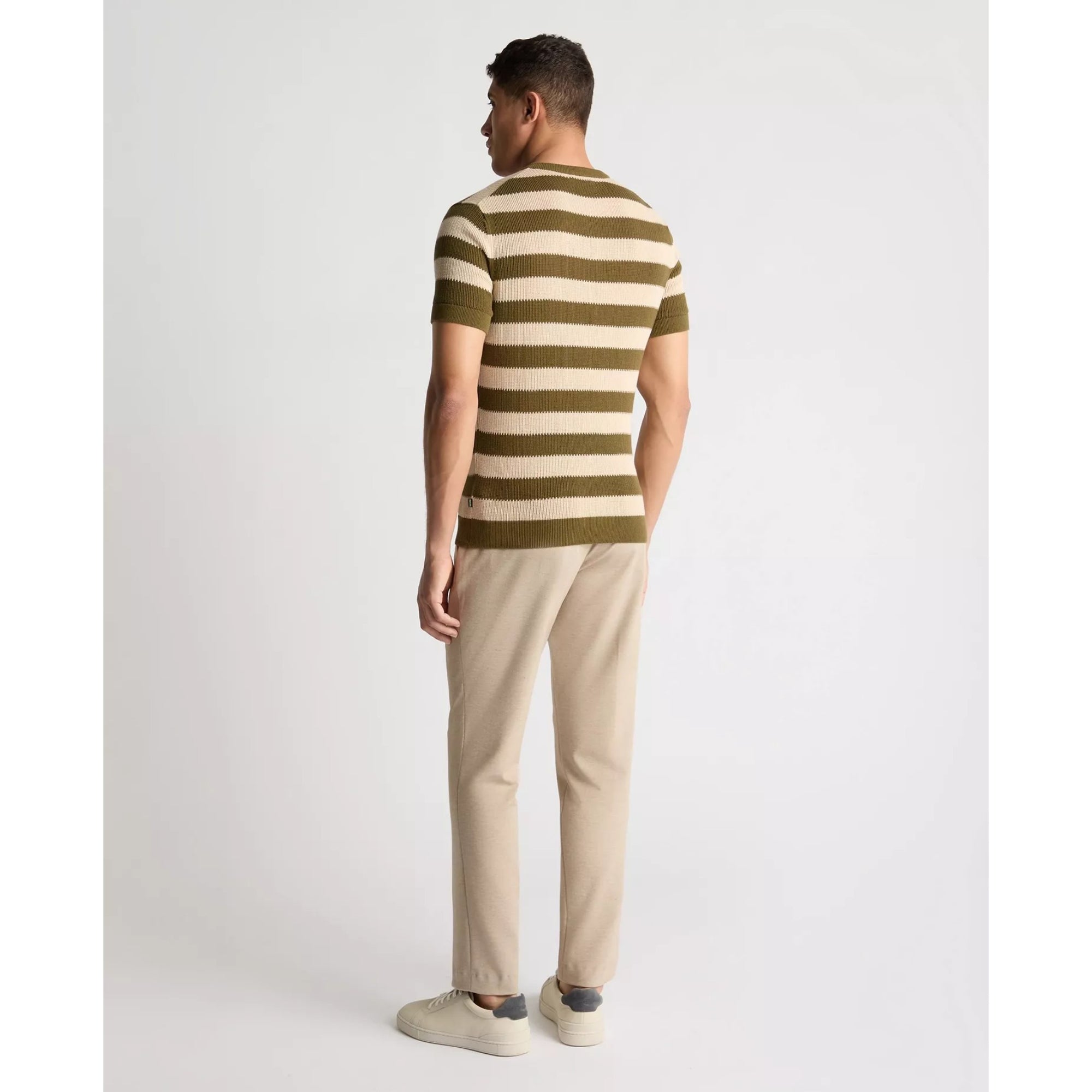 Man wearing a striped shirt and beige pants on a white background
